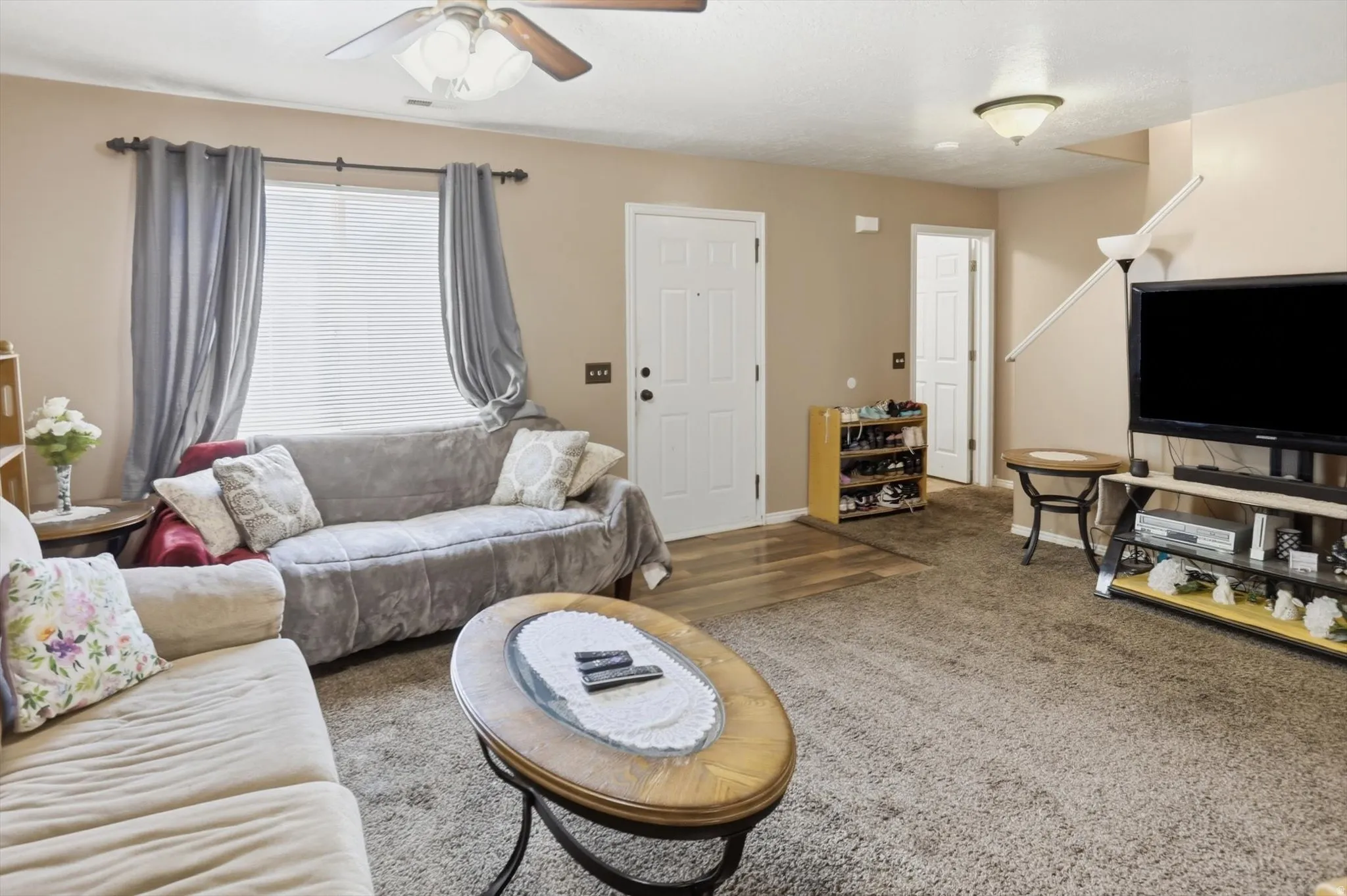Living room featuring neutral-toned carpet and a ceiling fan with integrated lighting
