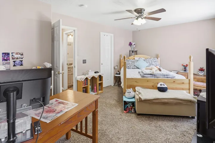Carpeted room featuring a ceiling fan, light-toned walls, and a wooden bed frame