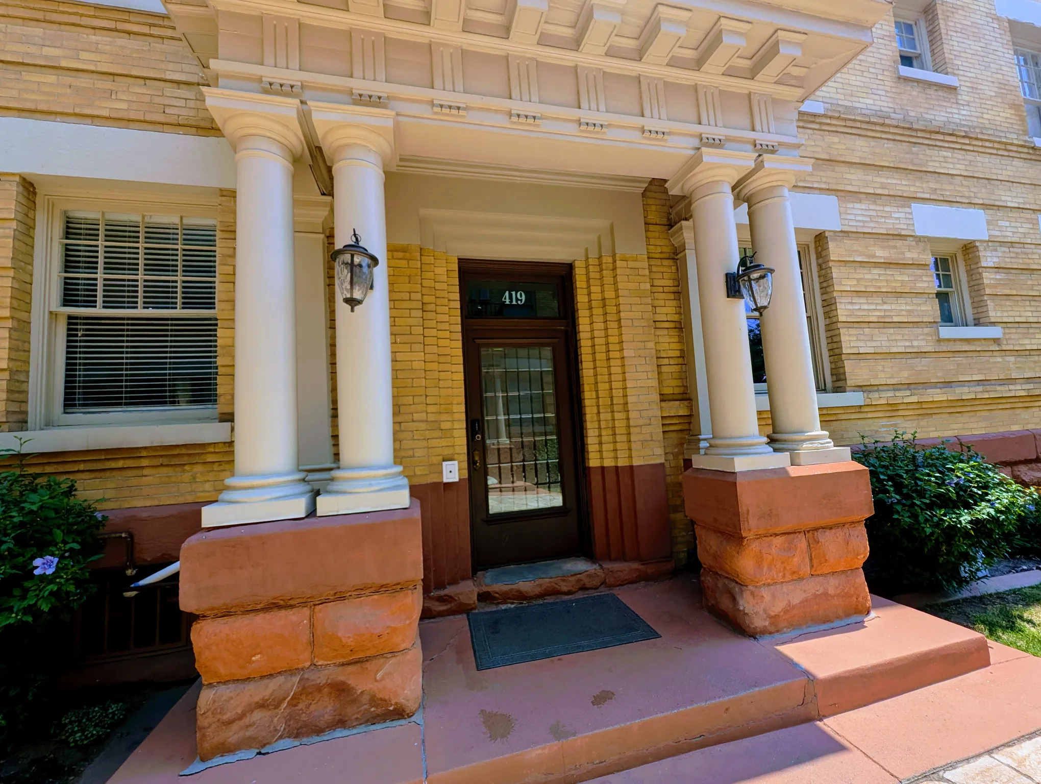 Entryway featuring a rich wood-finish door with glass inserts, flanked by decorative columns