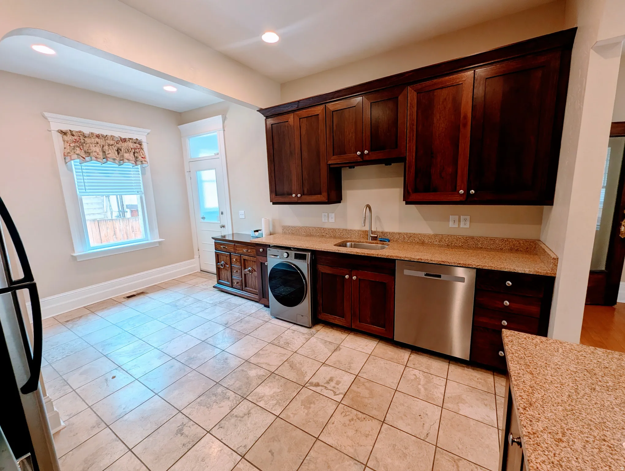 Kitchen featuring dark wood cabinetry, light-toned granite countertops, and stainless steel appliances