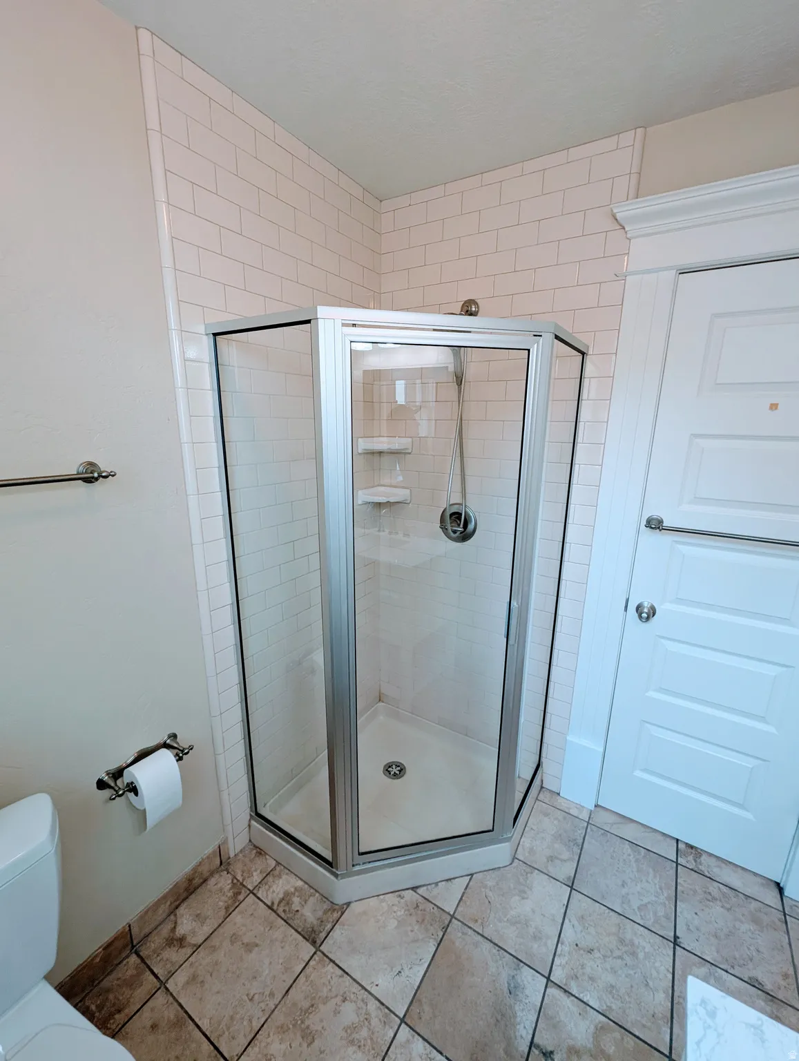Corner shower enclosure with clear glass panels, subway tile shower surround, and a coordinating shower base