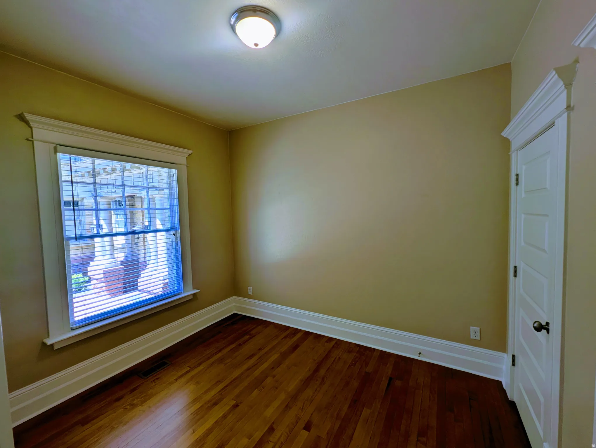 Room with rich wood-finish flooring and neutral wall tones