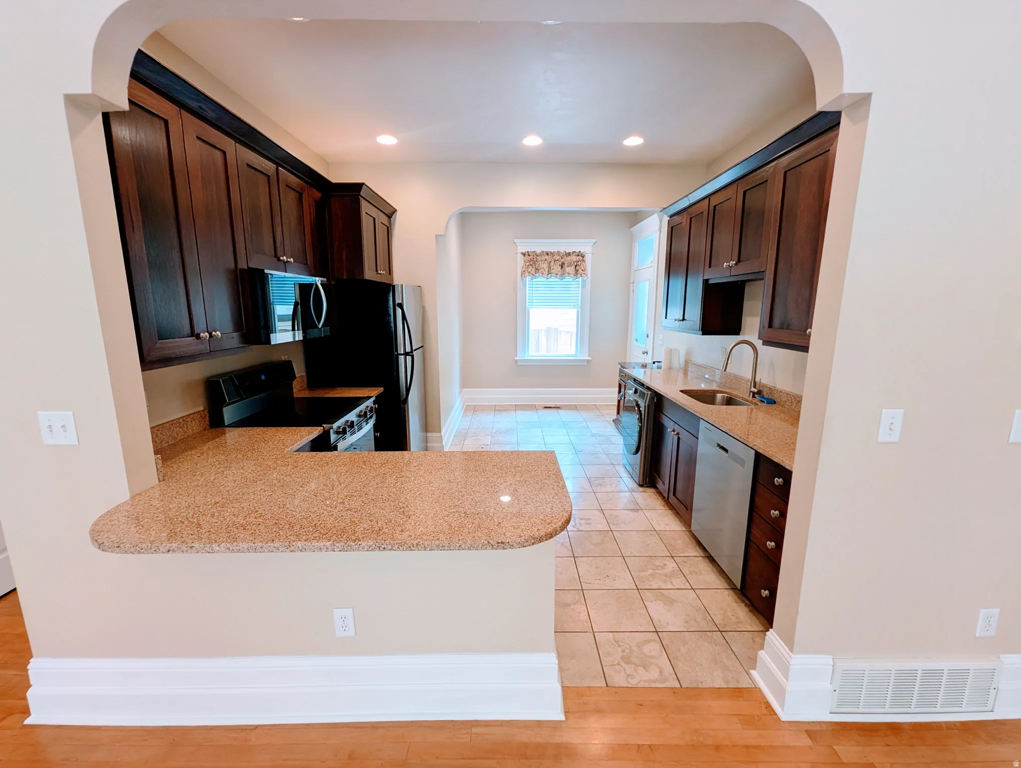 Kitchen featuring wood-finish cabinetry, light speckled countertops, and stainless steel appliances