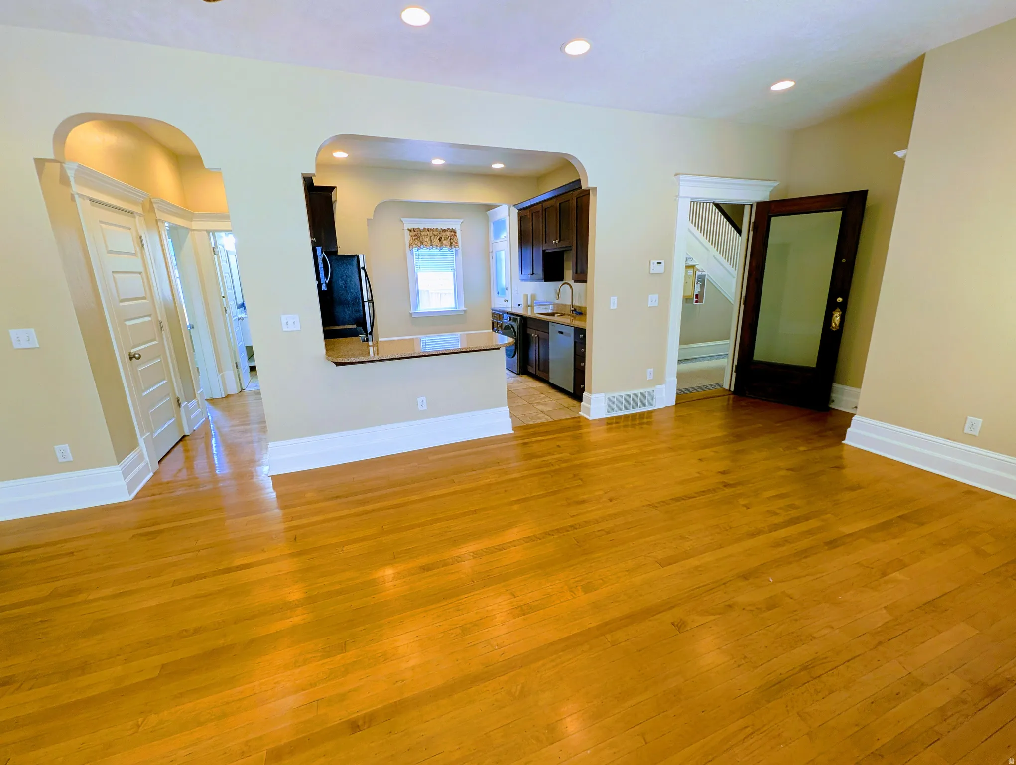 Hardwood flooring extends throughout this open-concept space, featuring recessed lighting and arched doorways
