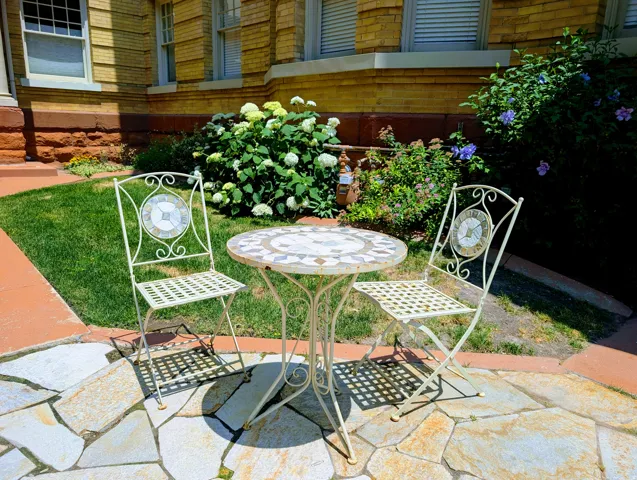 Flagstone patio area with a terracotta border, surrounded by manicured lawn and mature landscaping