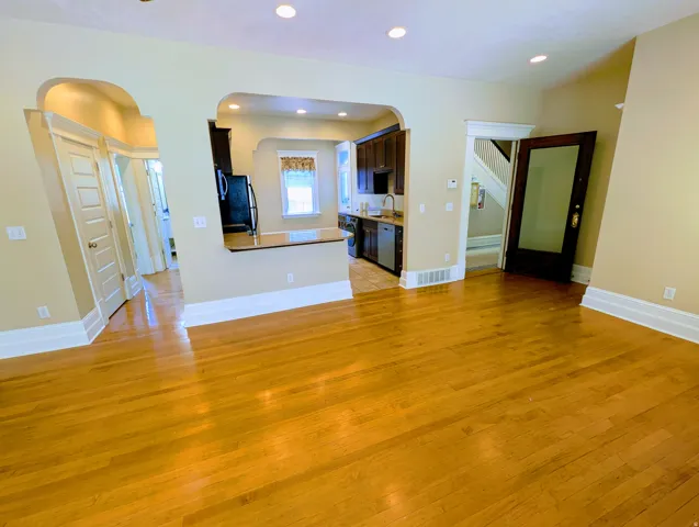 Hardwood flooring extends throughout this open-concept space, featuring recessed lighting and arched doorways