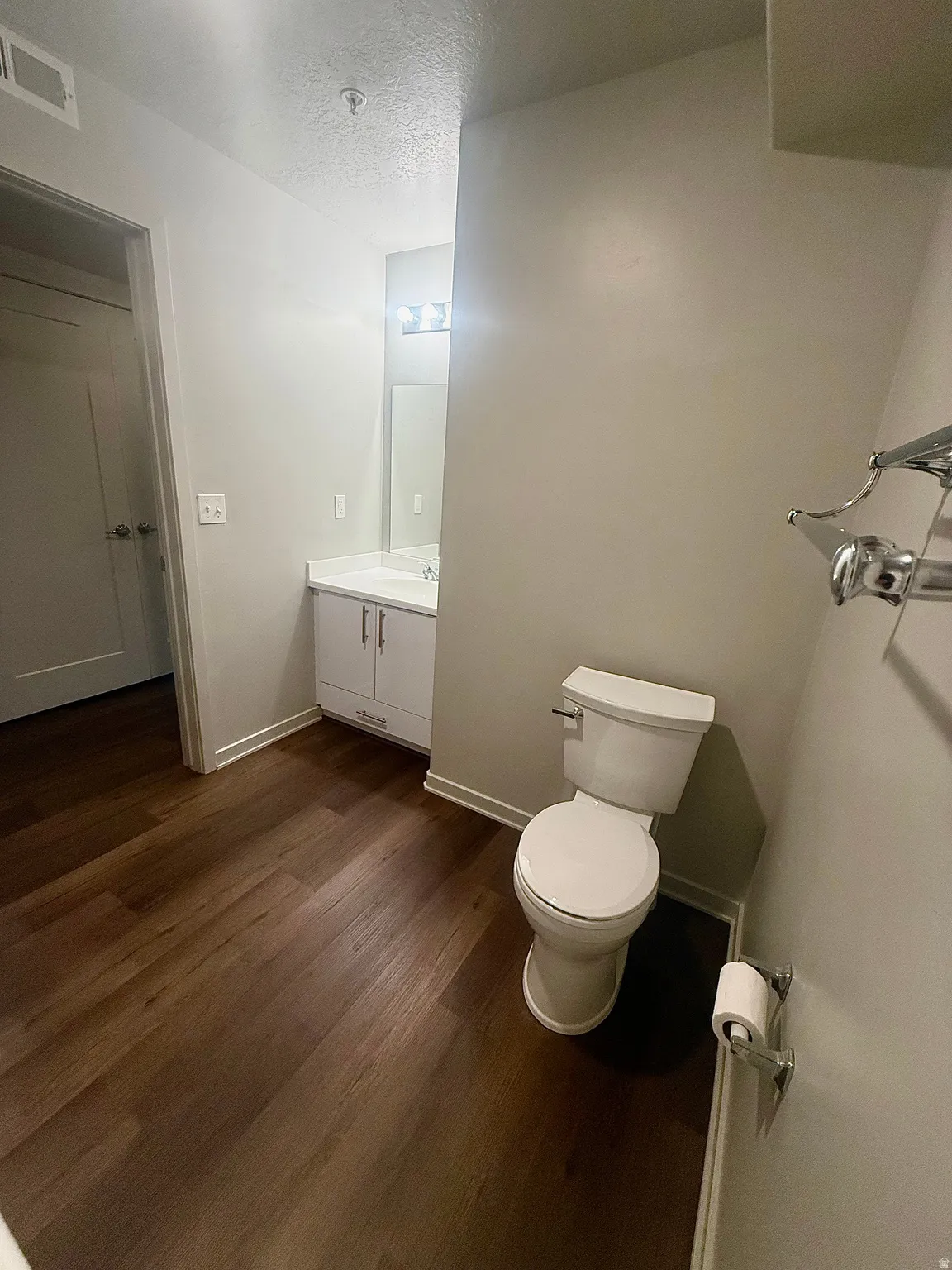 Bathroom featuring wood-finish flooring, a white vanity with built-in storage, a rectangular sink, and a modern vanity light fixture