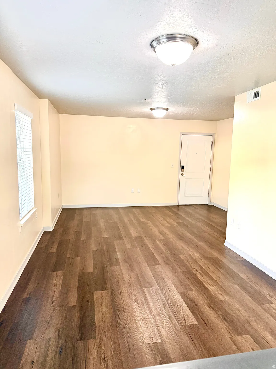 Spacious interior with wood-finish flooring, light-toned walls, and multiple ceiling-mounted light fixtures