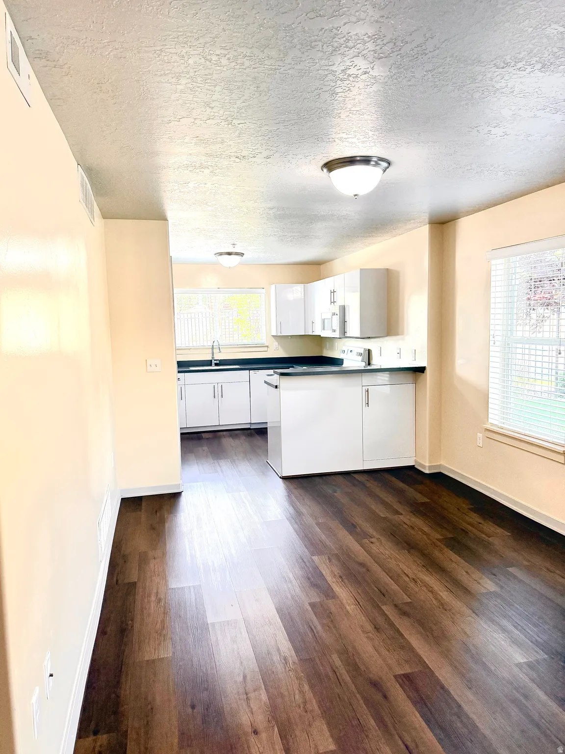 Contemporary kitchen with white cabinetry, dark countertops, and stainless steel sink