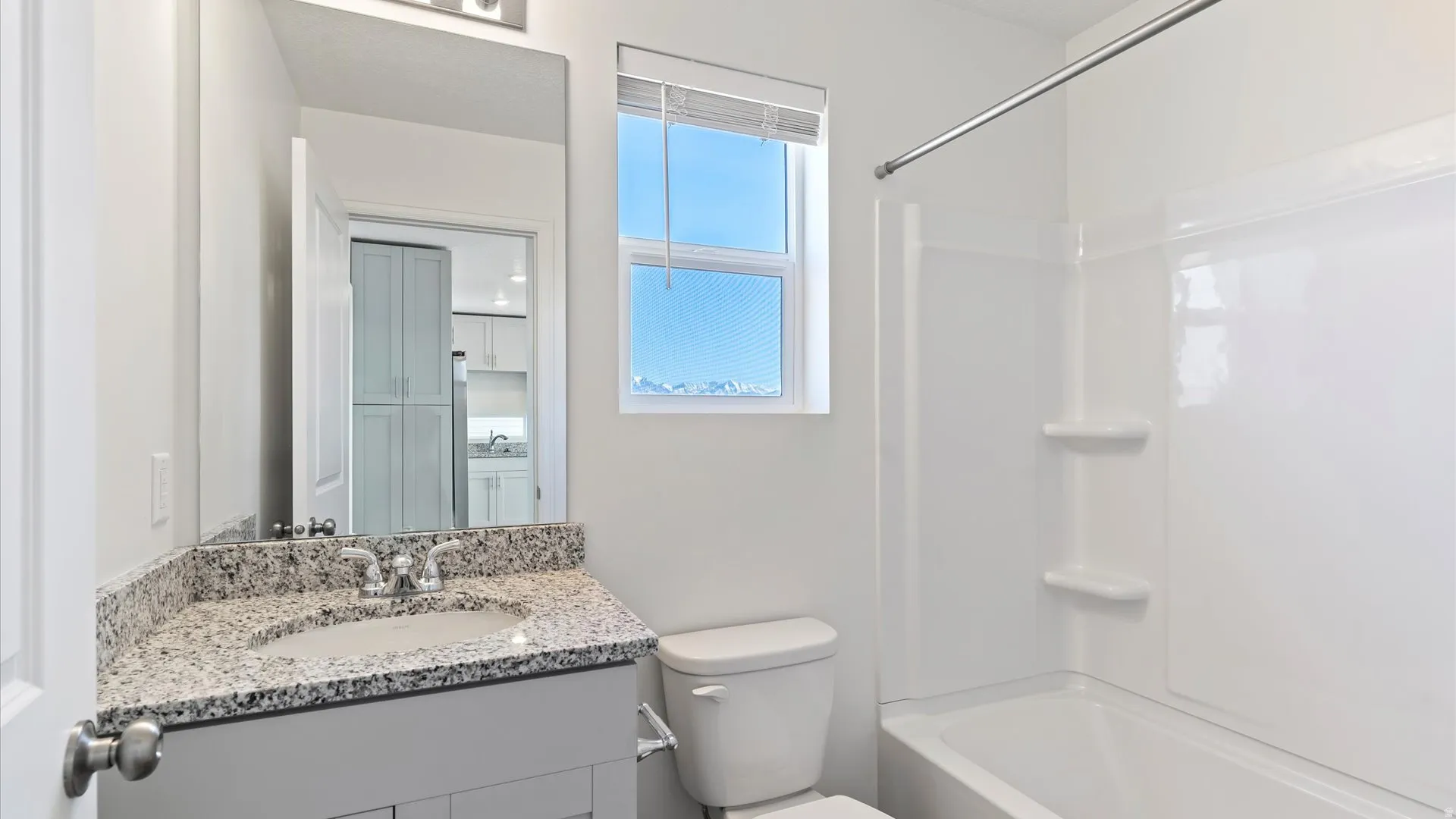 Bathroom featuring a single vanity with a granite countertop, undermount sink, and chrome faucet