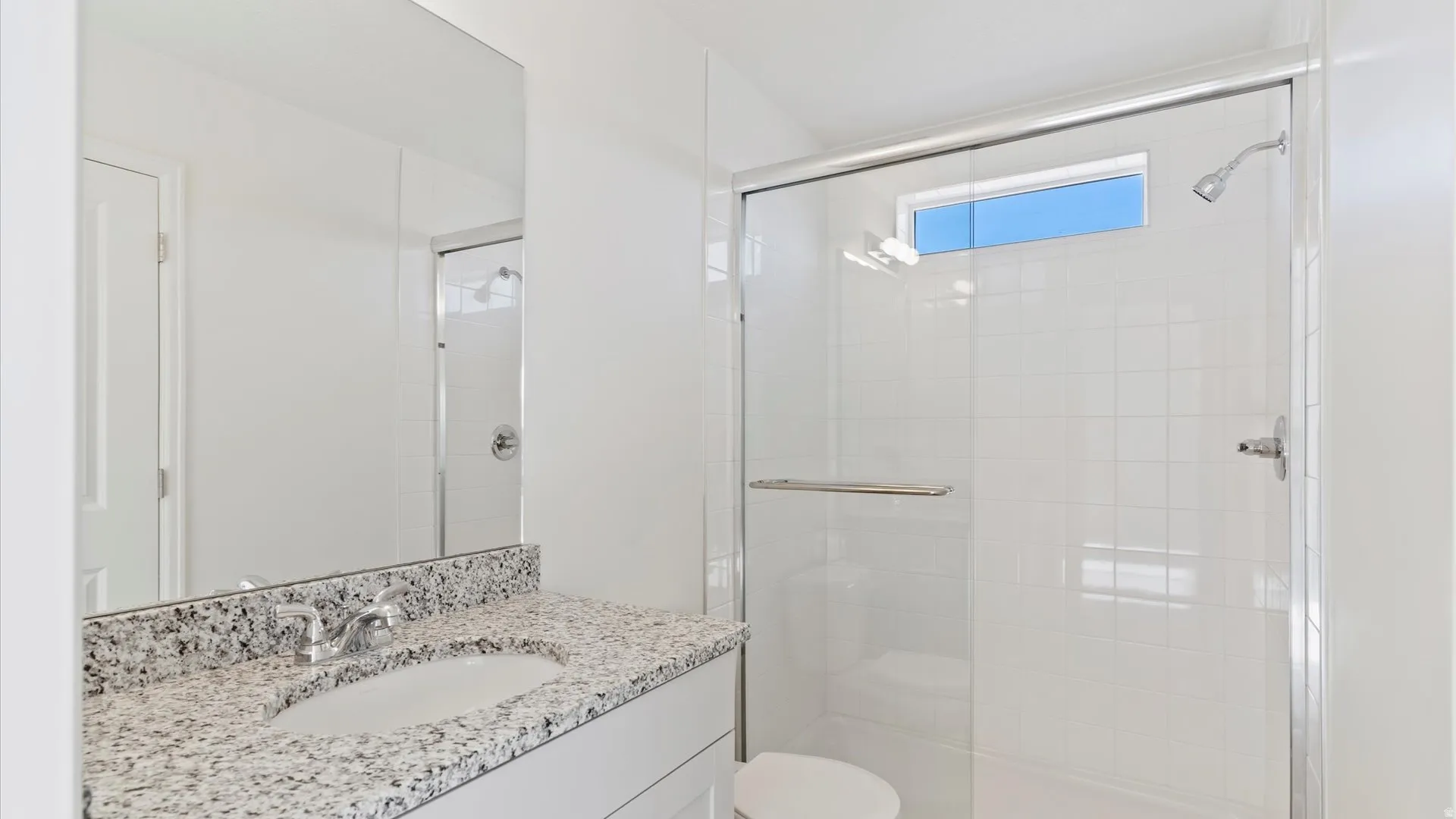 Modern bathroom featuring a glass-enclosed shower with tile surround and a transom window