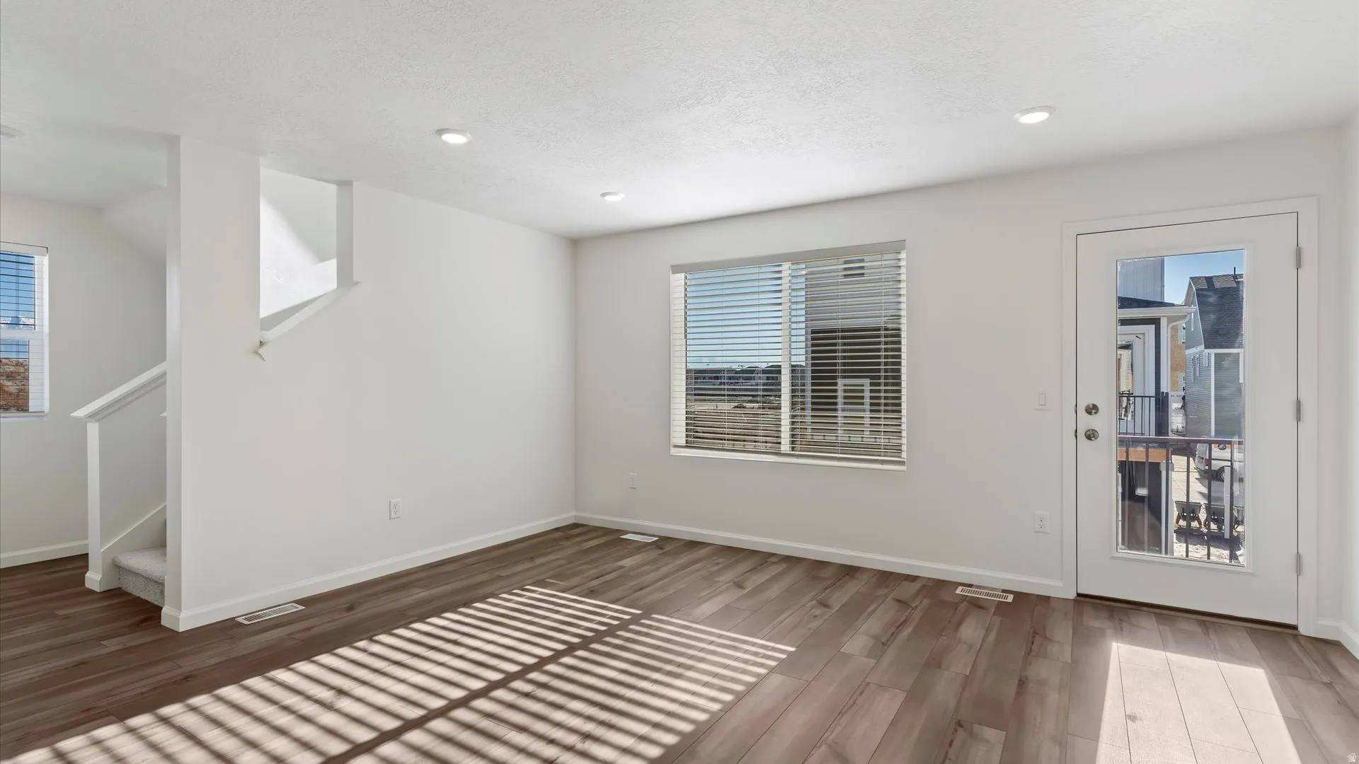 Spacious living area featuring wood-finish flooring, recessed lighting, and white walls