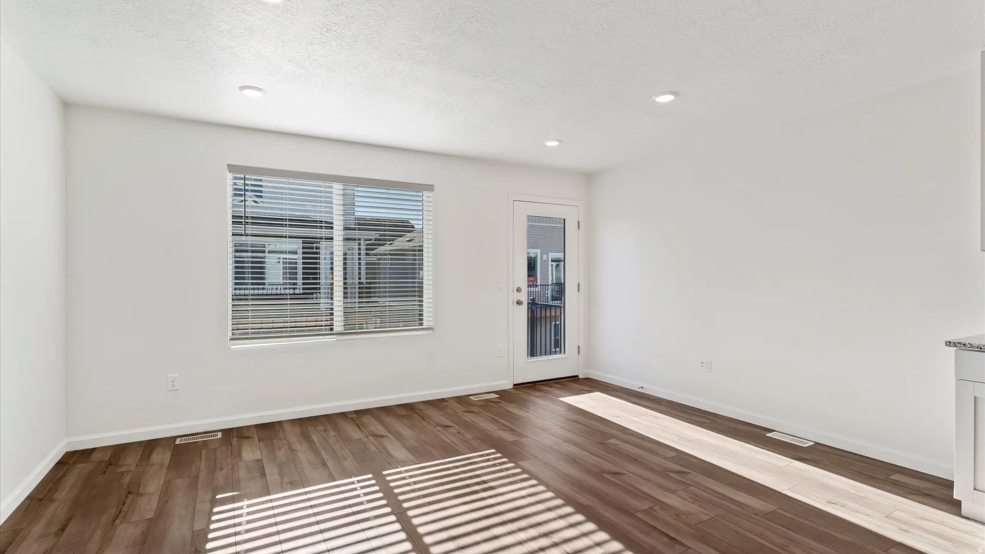 Open-concept room featuring wood-finish flooring, recessed lighting, and a glass-paneled door