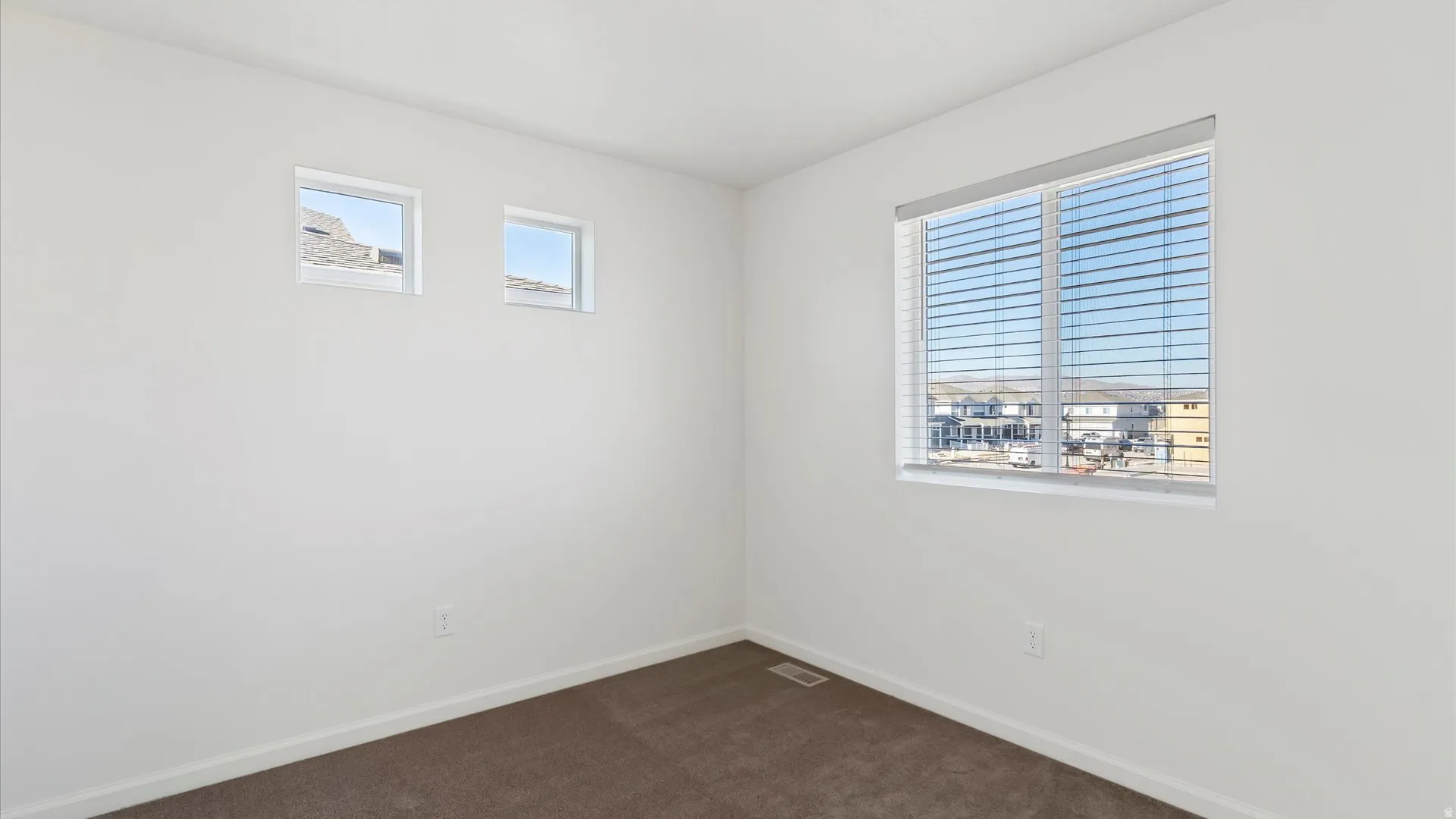 Neutral tone walls with a large window featuring horizontal blinds