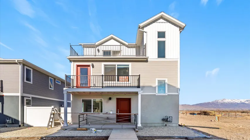 Multi-level exterior with vertical and horizontal siding, stucco finishes, and a top-floor balcony
