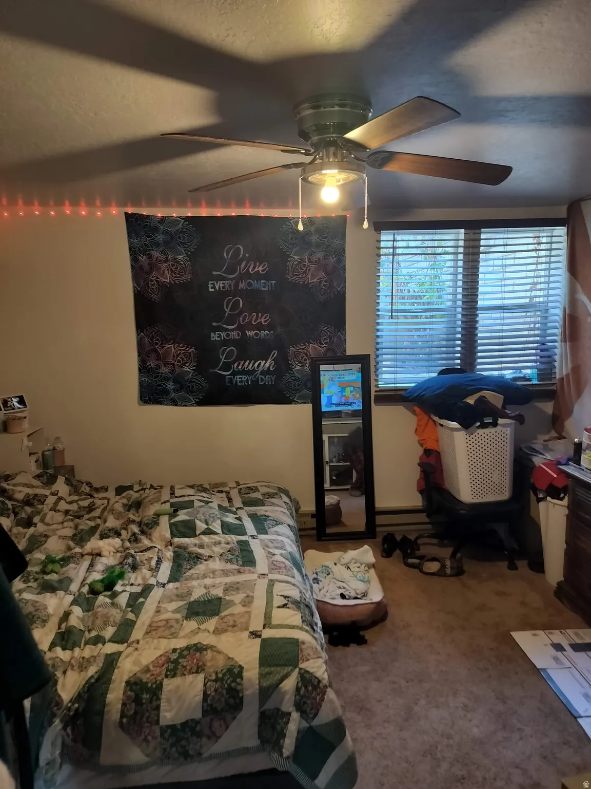 Room featuring a ceiling fan with integrated lighting, a window with horizontal blinds, and neutral-toned wall-to-wall carpeting