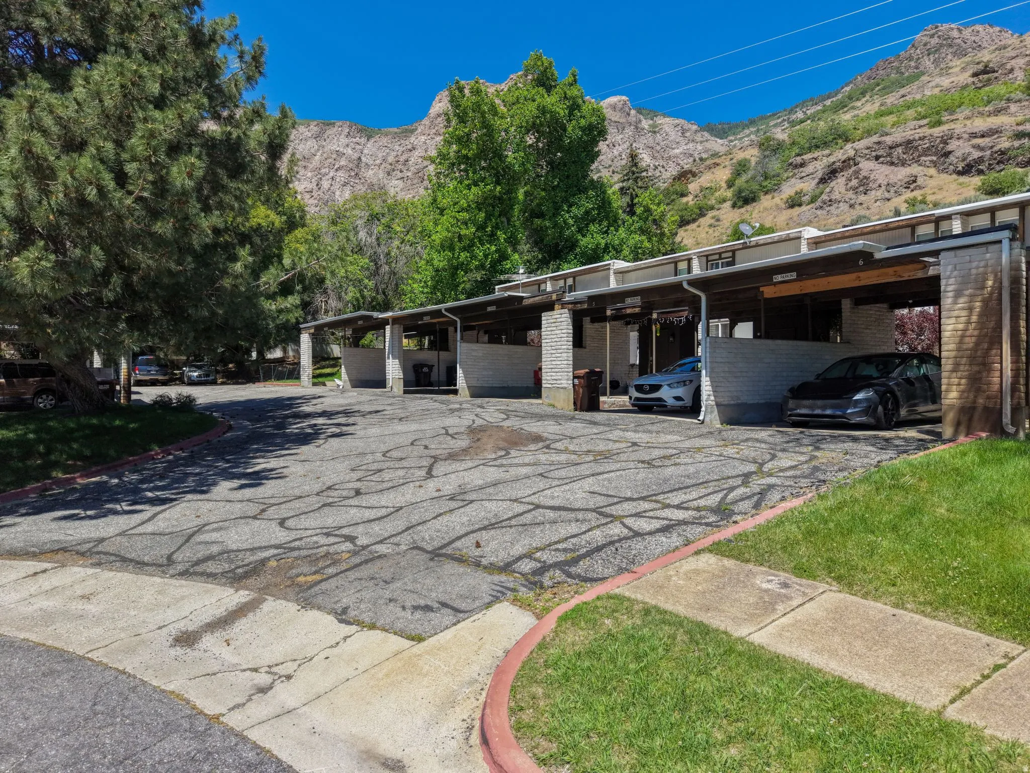 Covered parking spaces with brick columns and a backdrop of mountainous terrain