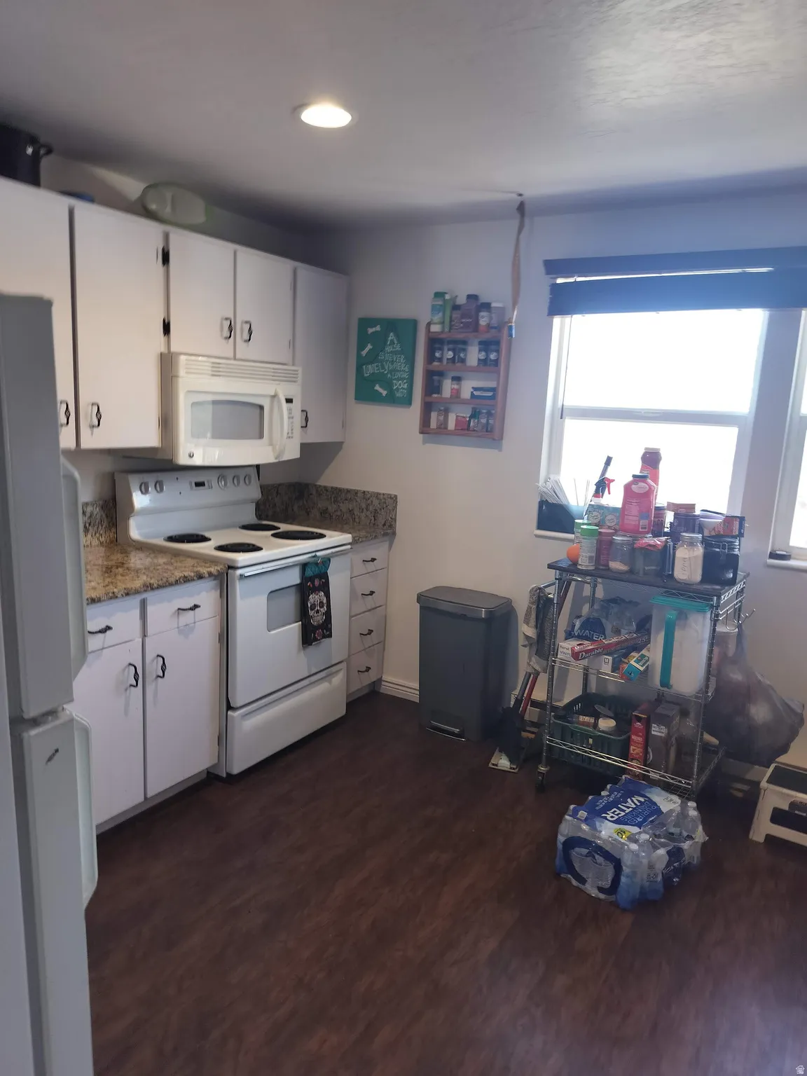 Kitchen featuring white cabinetry, a built-in microwave, a white electric range, and granite-patterned countertops