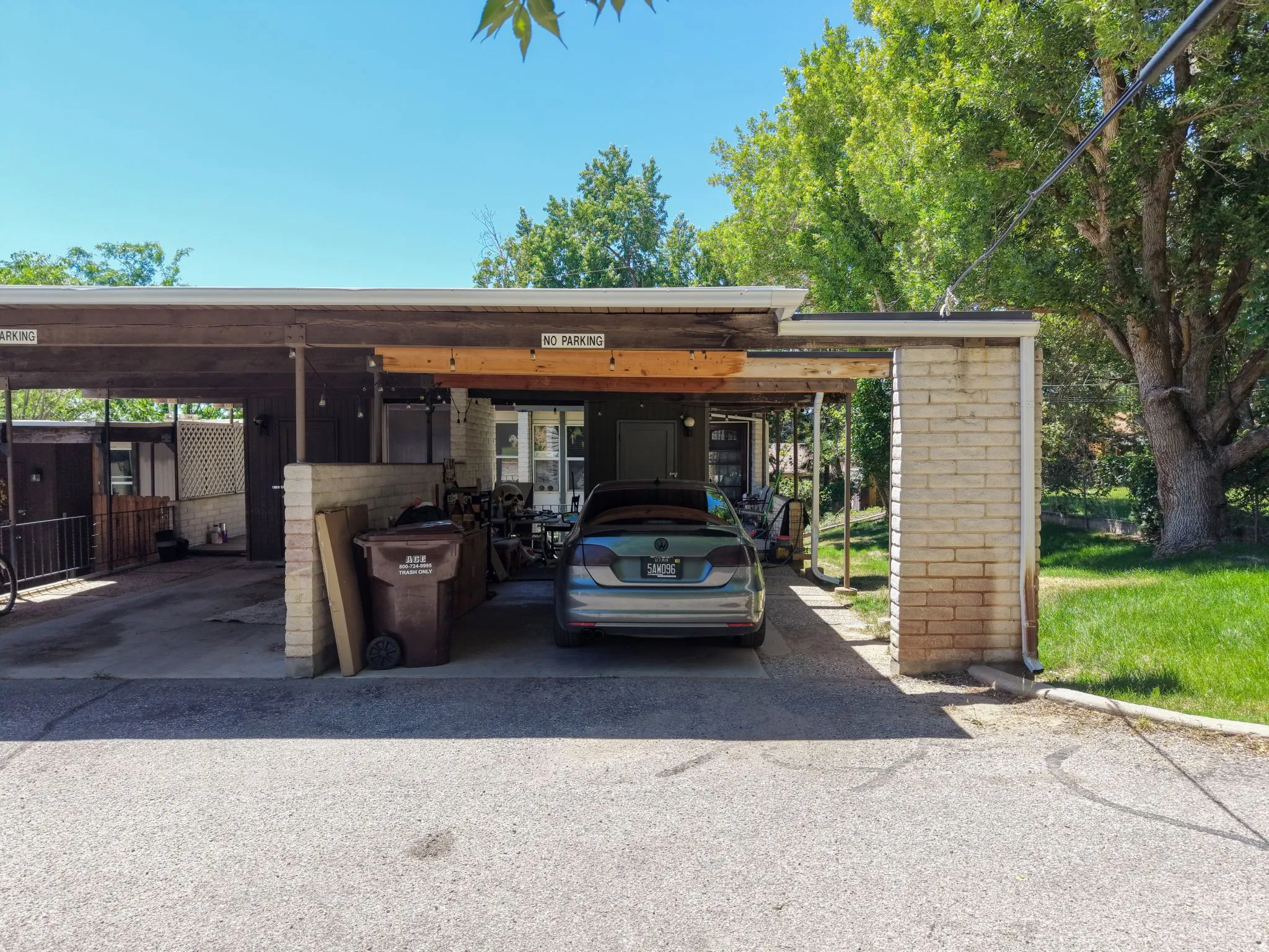 Carport parking structure featuring exposed wood beams and brick pillars