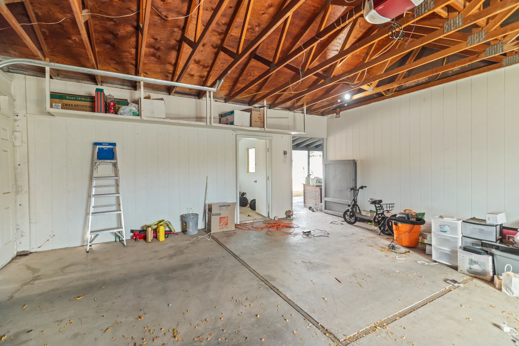 Spacious garage featuring exposed wood beam ceilings and a concrete floor