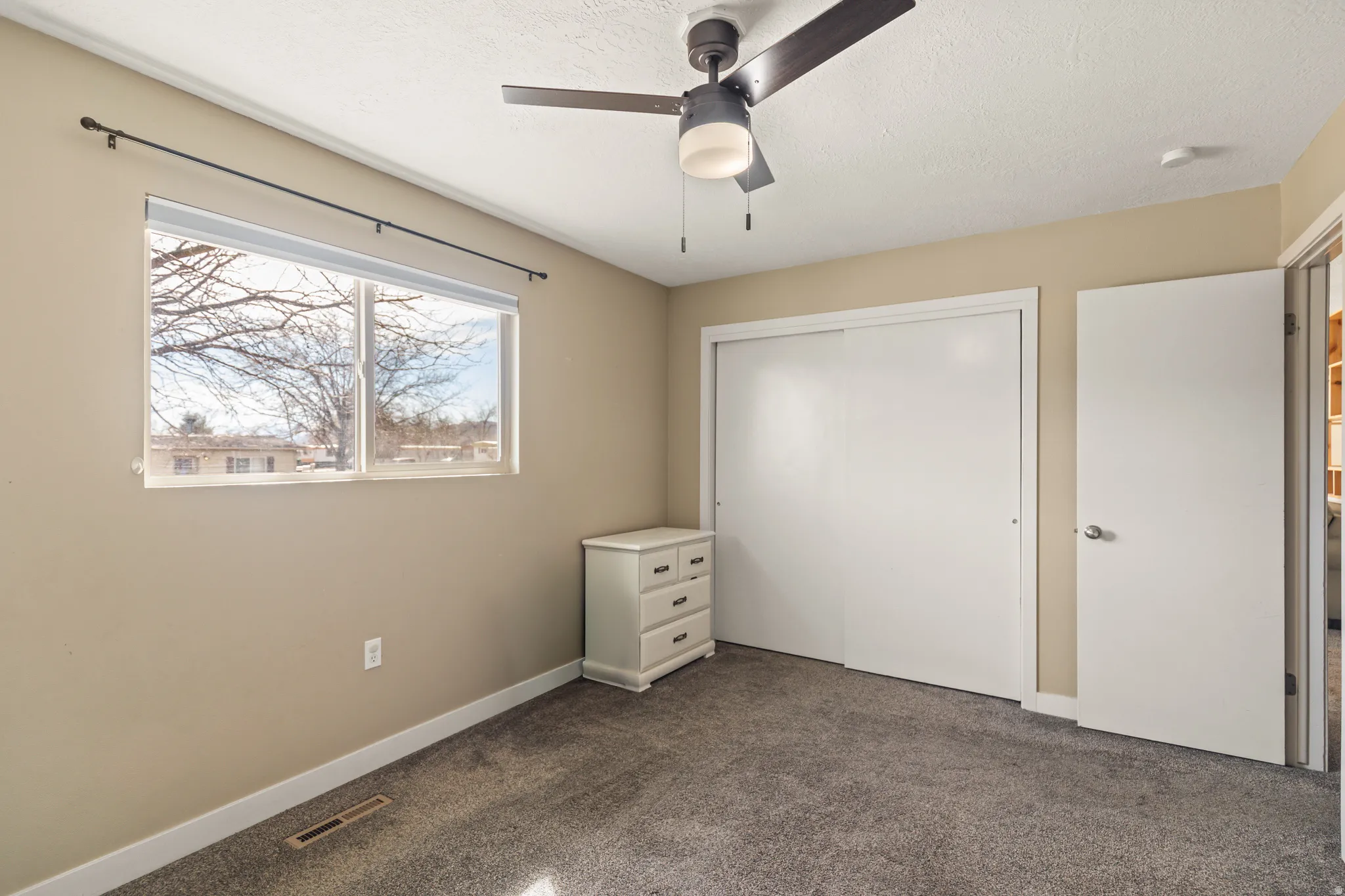 Windowed room featuring a ceiling fan with integrated lighting, neutral wall tones, and plush carpeting