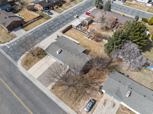 Aerial perspective highlighting the property with a gray shingle roof, a paved driveway, and established trees