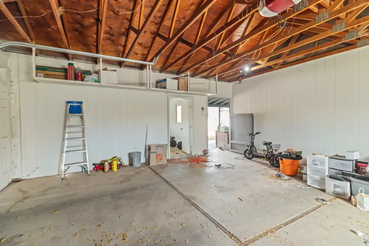 Spacious garage featuring exposed wood beam ceilings and a concrete floor