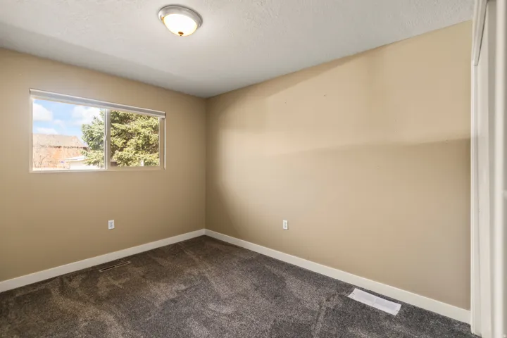 Neutral-toned interior room featuring a window with exterior tree and roofline visible