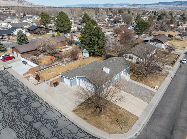 Ranch-style residence featuring a light blue exterior, a gray shingled roof, an attached two-car garage, and a combination concrete and gravel driveway