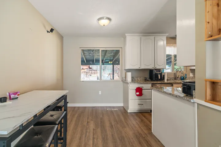 Kitchen area featuring white cabinetry, granite-style countertops, and wood-finish flooring