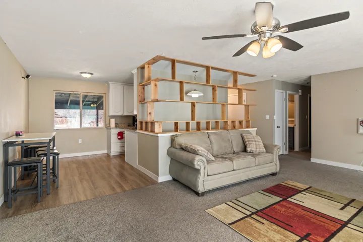 Open concept living area featuring a built-in shelving unit, wood-finish flooring, and a ceiling fan with integrated lighting