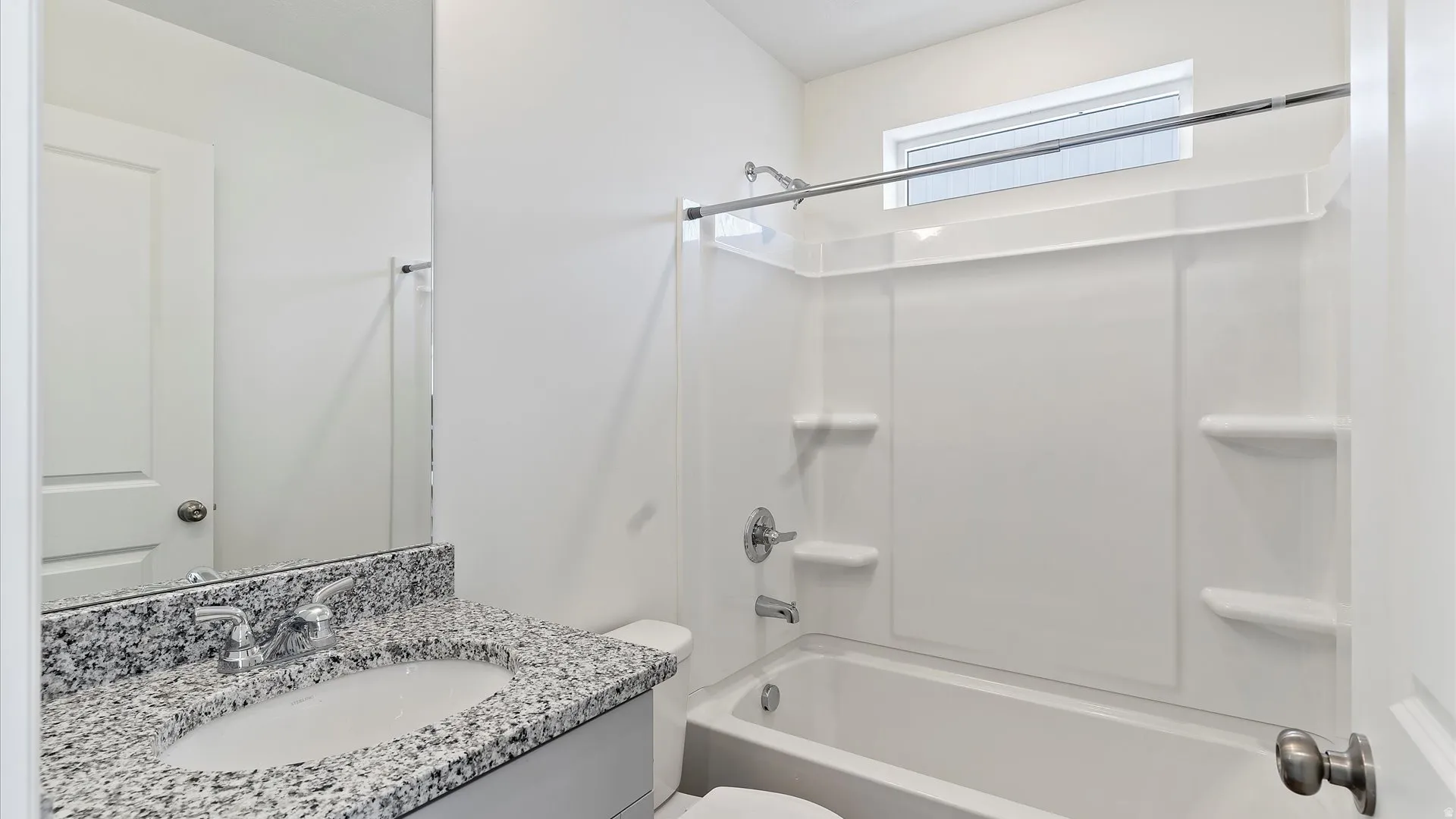 Bathroom featuring a white vanity with a speckled countertop and an integrated sink, polished chrome faucet, and a large wall-mounted mirror
