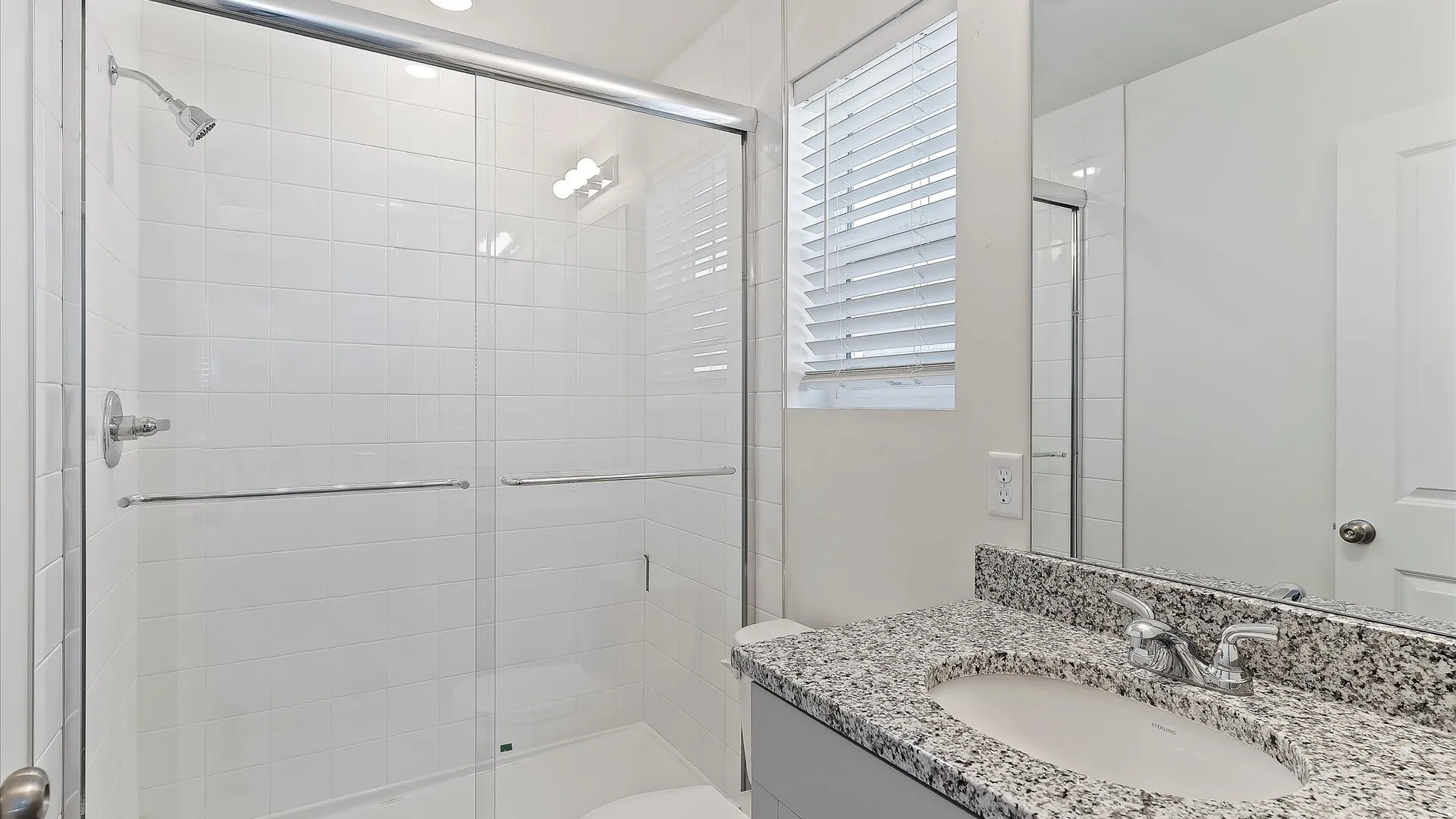Bathroom featuring a glass-enclosed shower with white subway tile surround, granite countertop vanity, integrated sink, and chrome fixtures