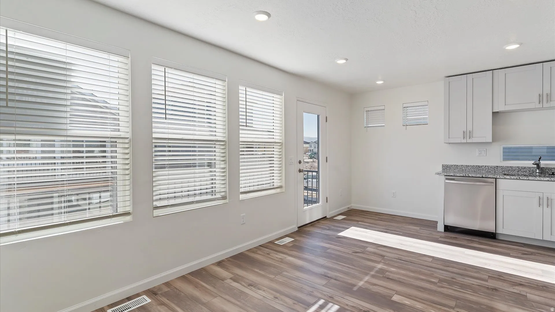 Open-concept living space featuring wood-finish flooring, recessed lighting, and a white color palette