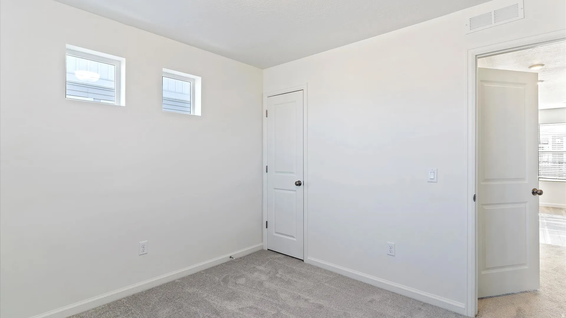 Neutral white wall finishes with a light gray carpeted floor