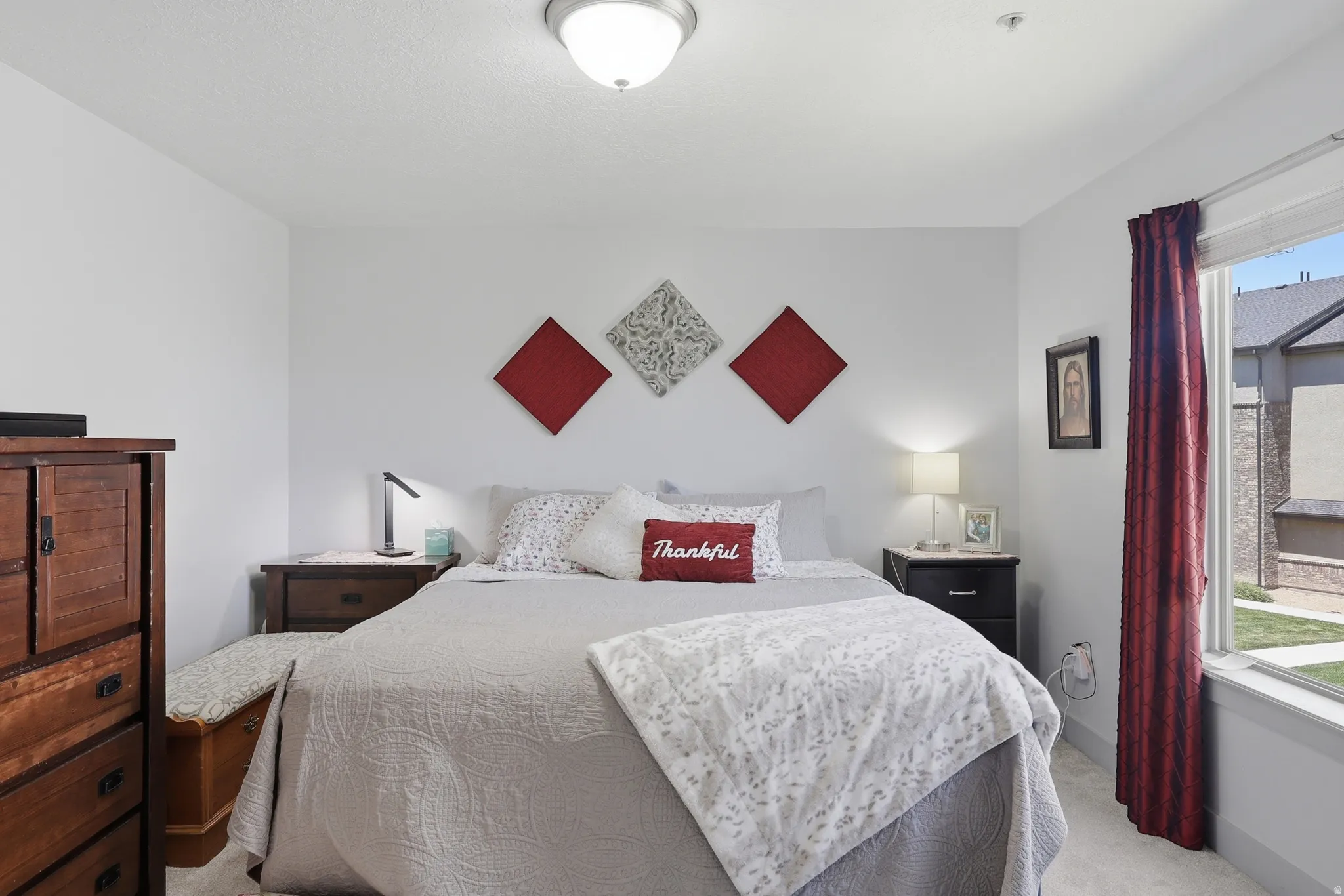 Carpeted bedroom featuring a large window with vertical blinds, a flush mount ceiling light, and light-colored walls