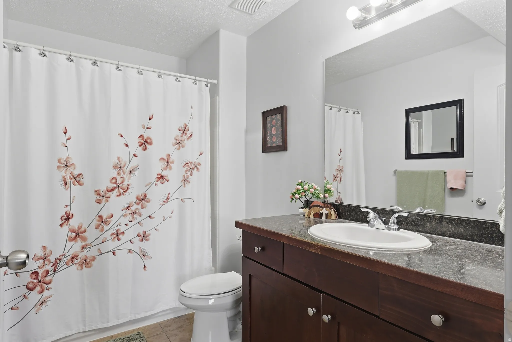 Bathroom featuring a dark wood-finish vanity with an undermount sink, a dark stone-look countertop, and a large wall-mounted mirror