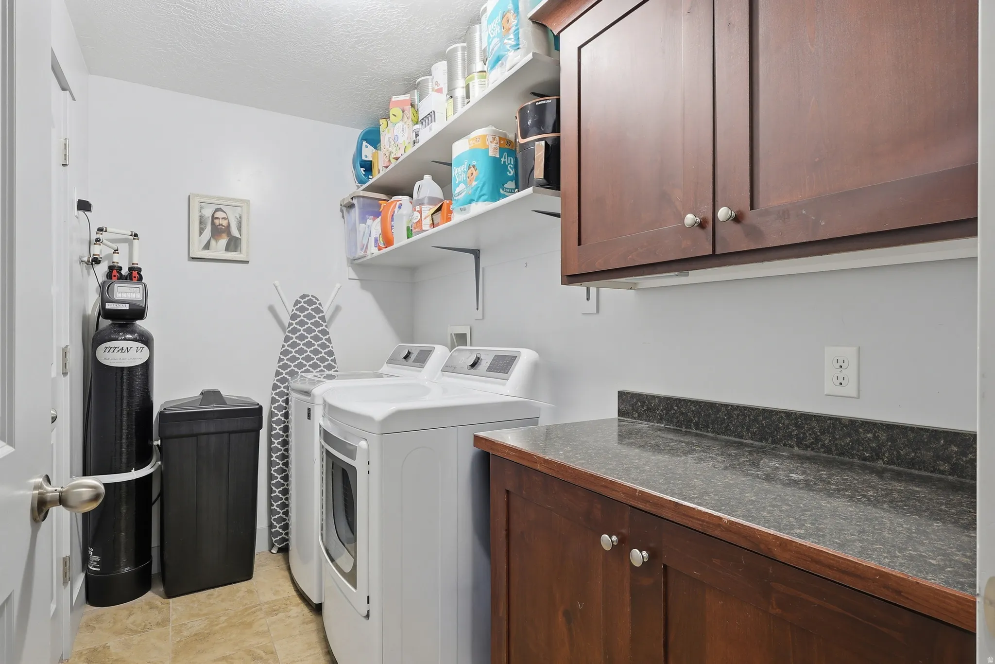 Dedicated laundry area featuring a tile floor, white walls, and built-in shelving