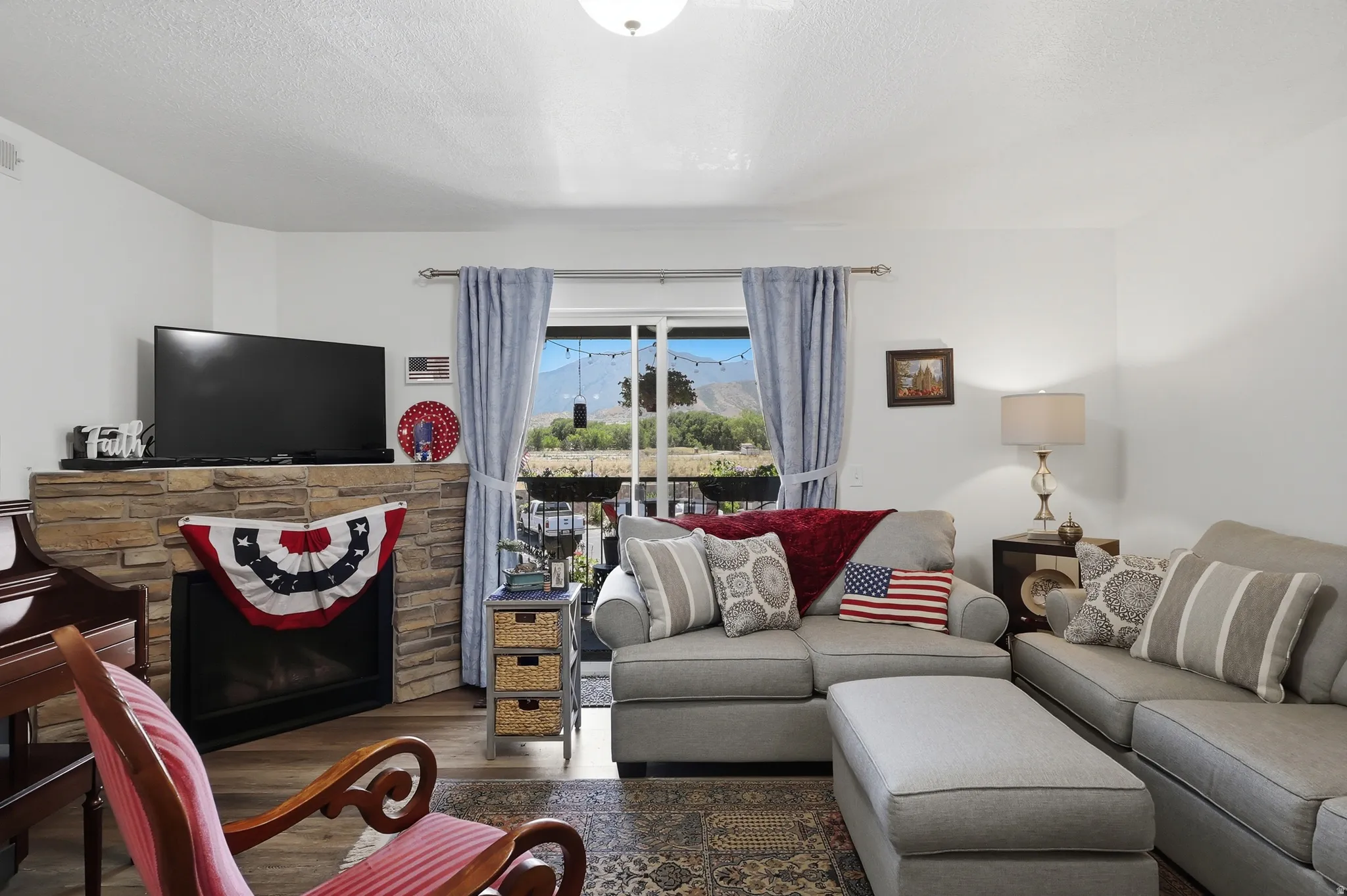 Living area featuring a stone-clad fireplace, wood-finish flooring, and a sliding glass door