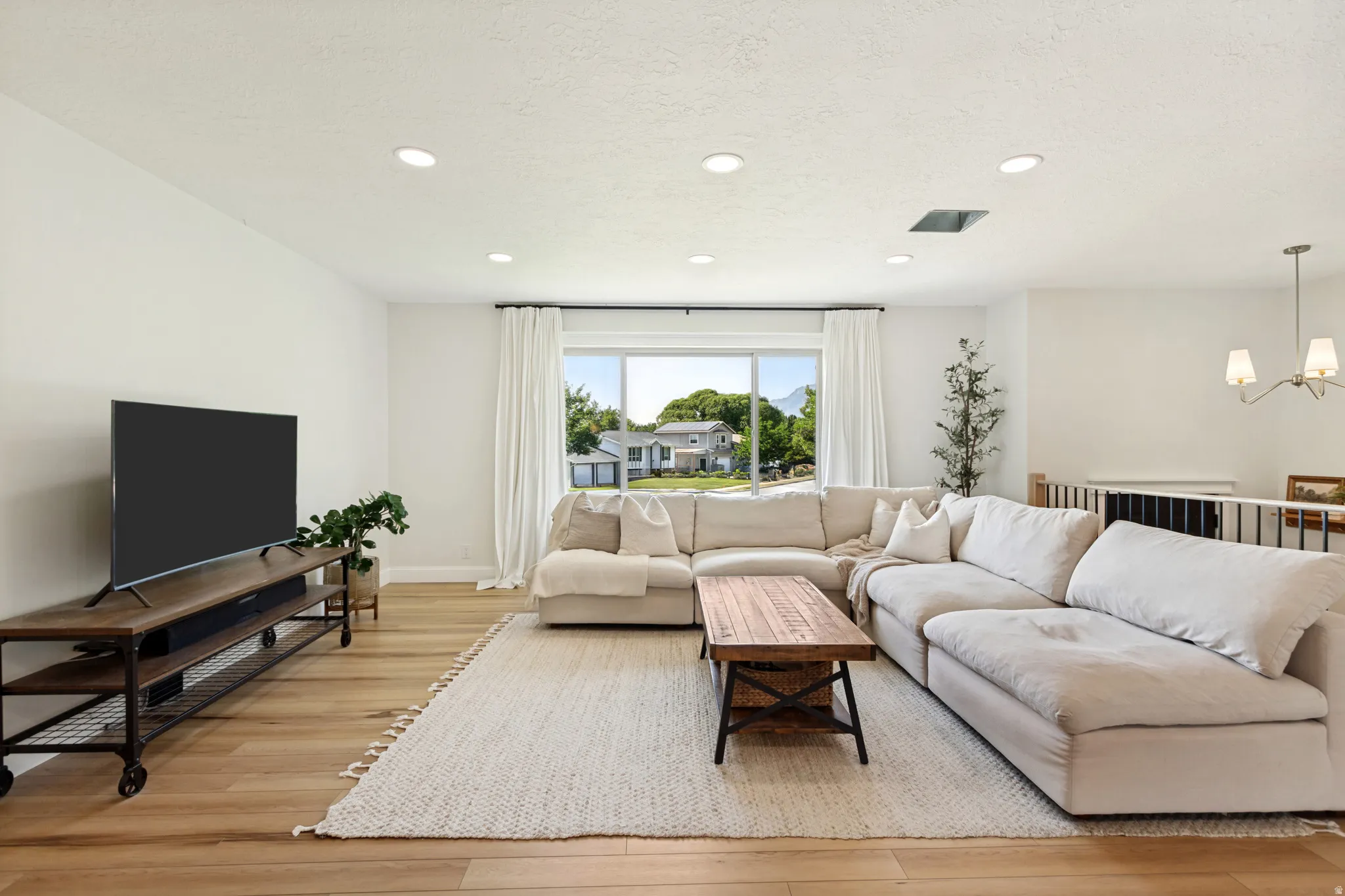 Bright living area featuring wood-finish flooring, recessed ceiling lighting, and crisp white walls