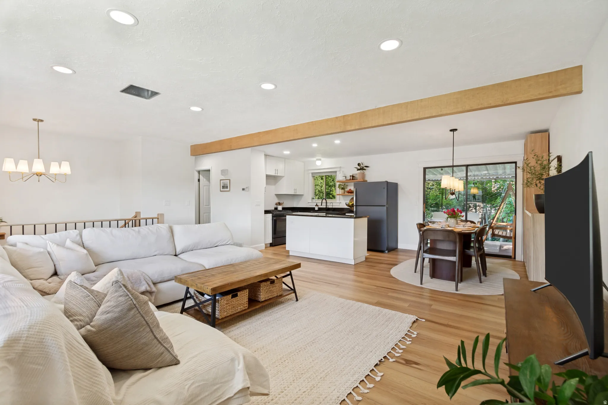 Open concept living space featuring recessed lighting, a decorative wood beam, wood-finish flooring, a kitchen island with seating, and sliding glass doors to the exterior