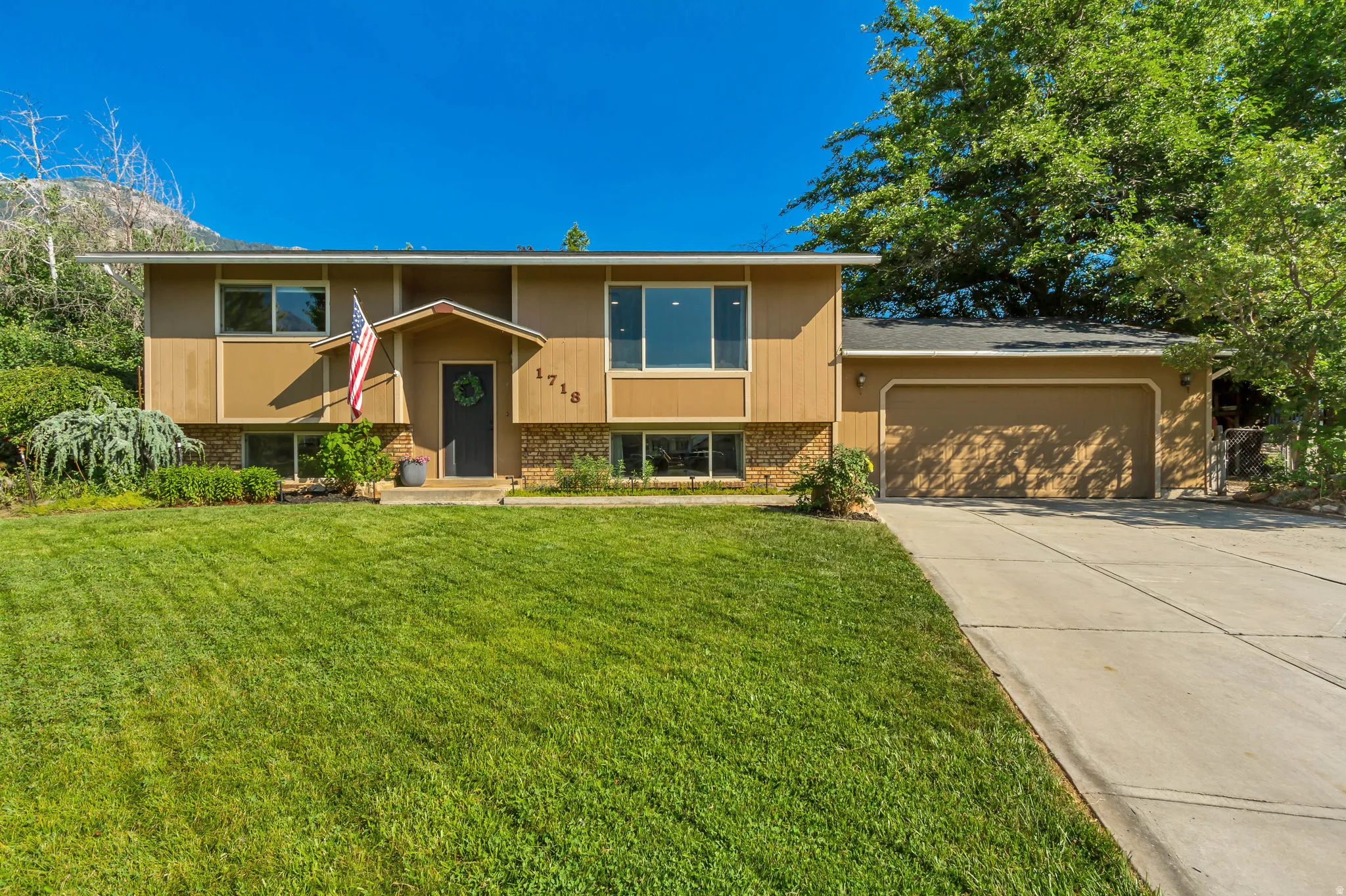 Split-level residence featuring a two-car garage, established front landscaping, and a concrete driveway