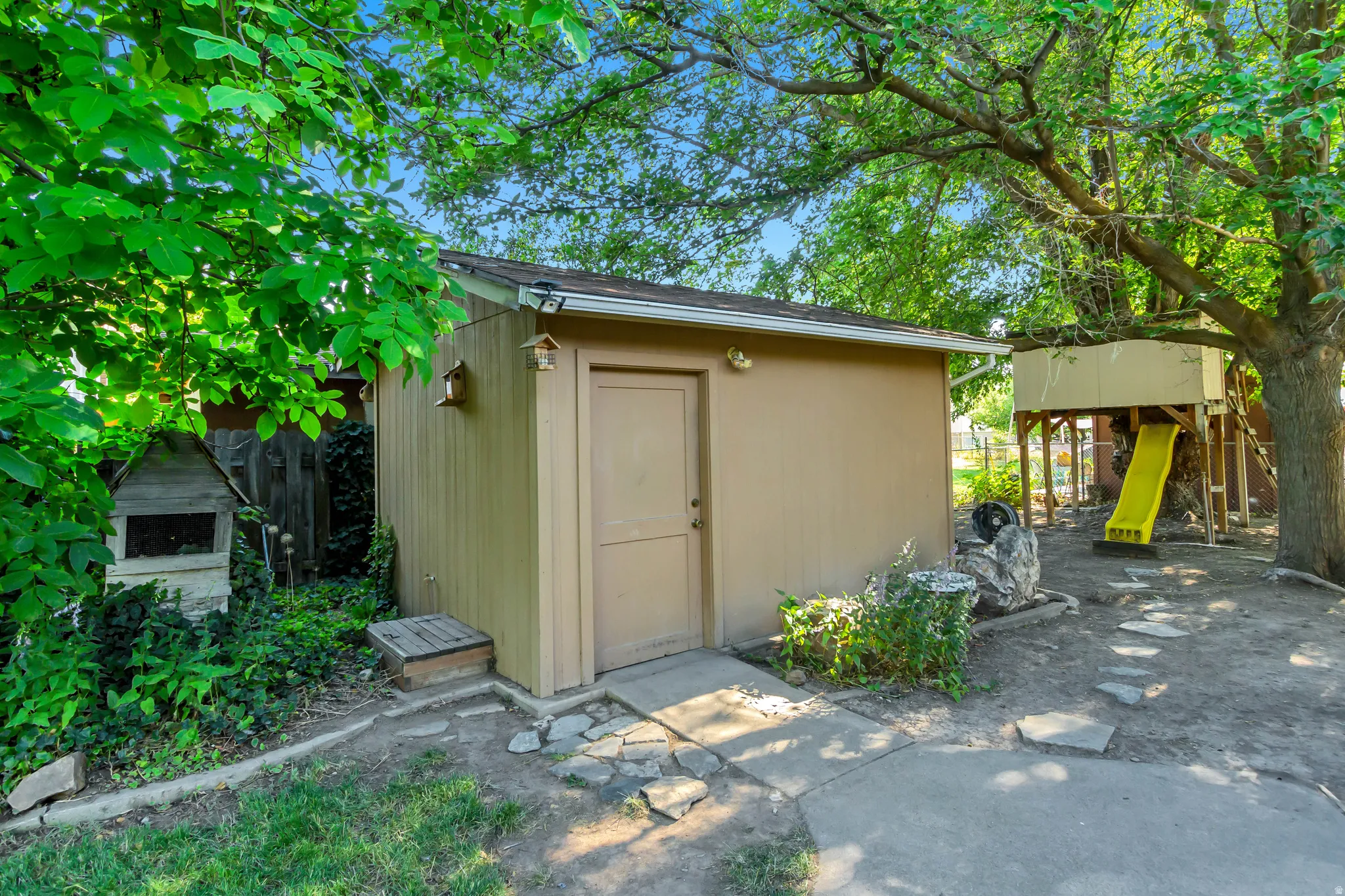 Detached storage shed with a light-colored exterior and a single entry door