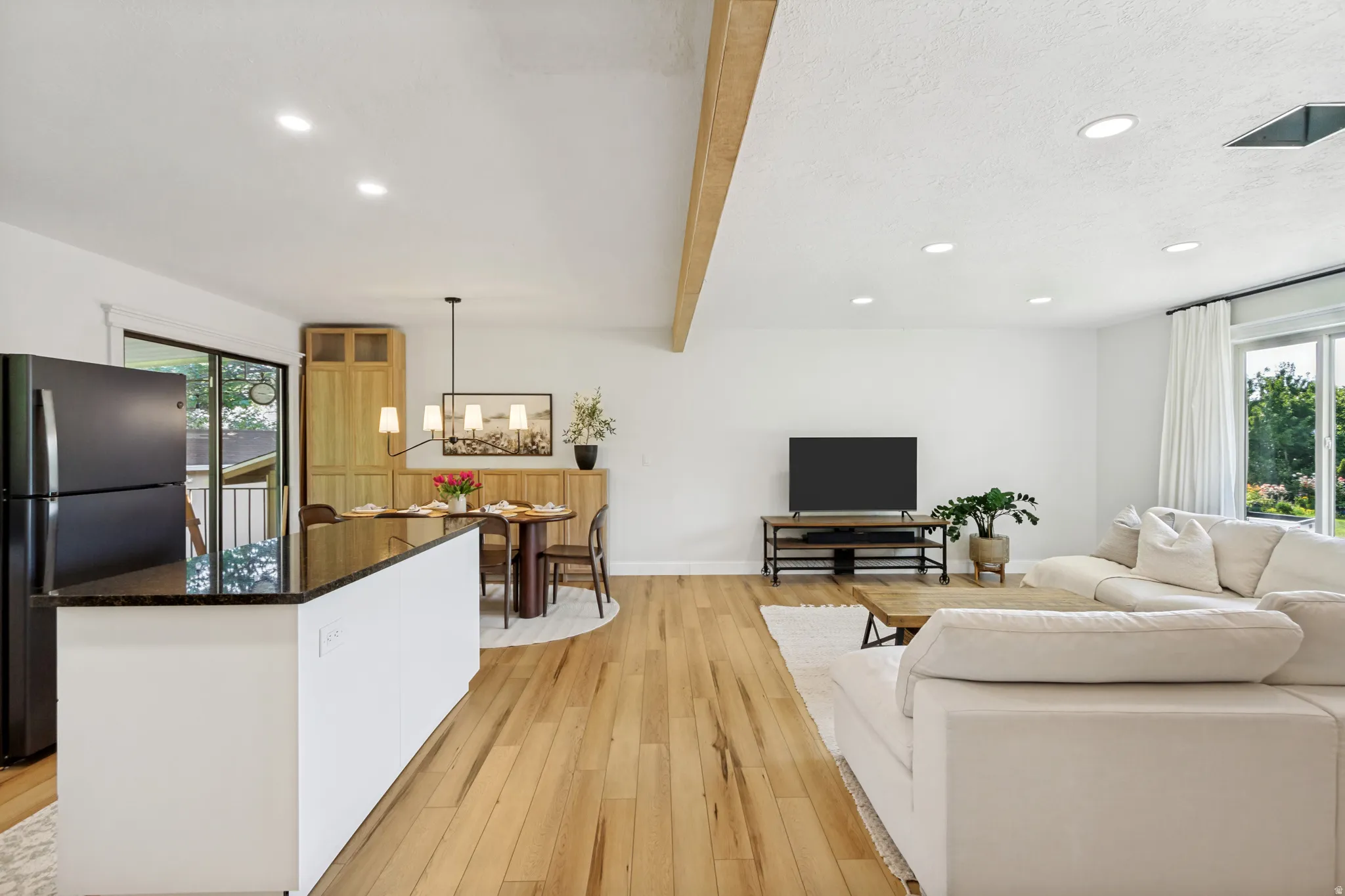 Open-concept living space featuring wood-finish flooring, recessed lighting, and a white color palette