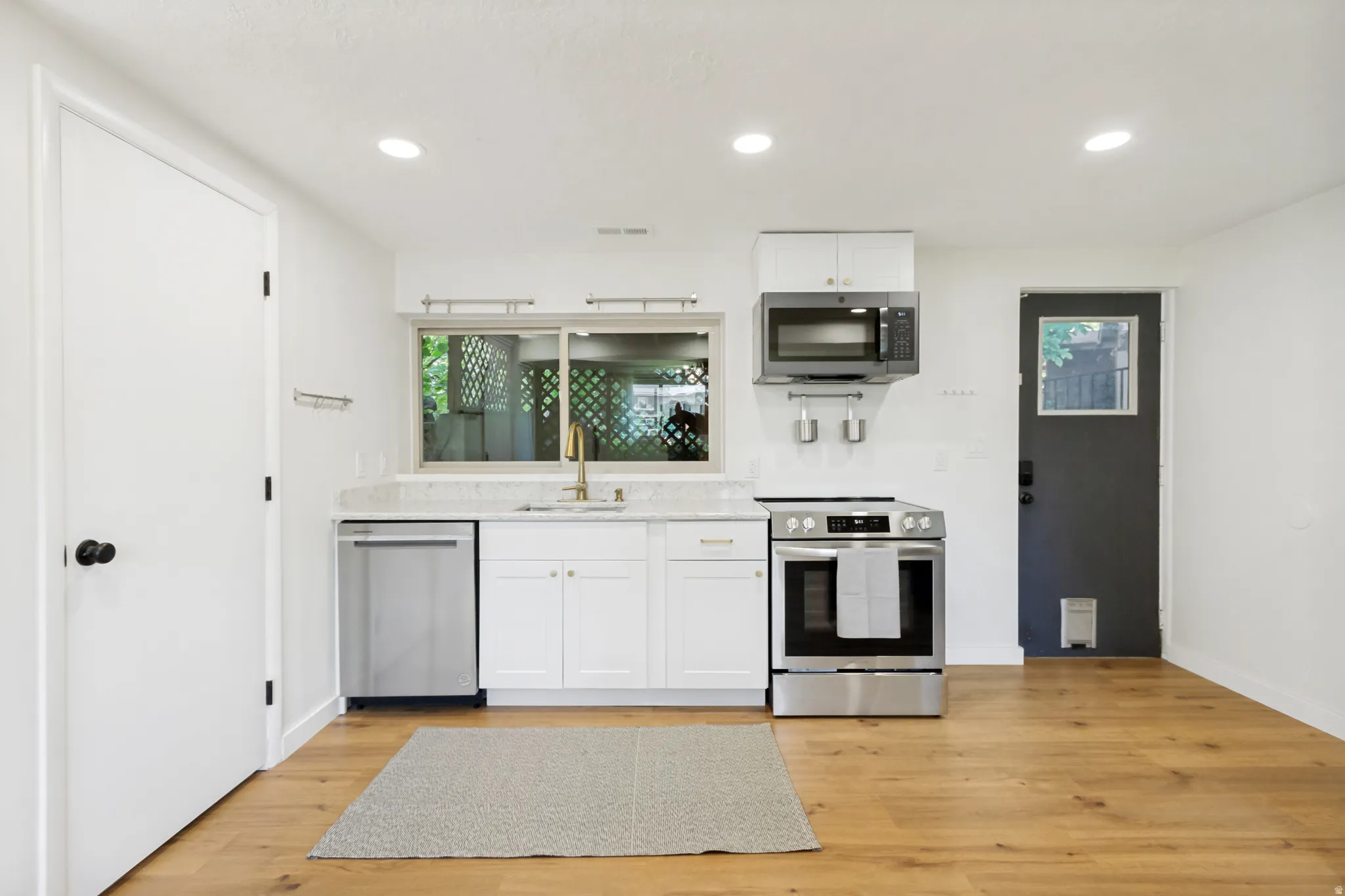 Bright kitchen area featuring wood-finish flooring, recessed lighting, and white cabinetry