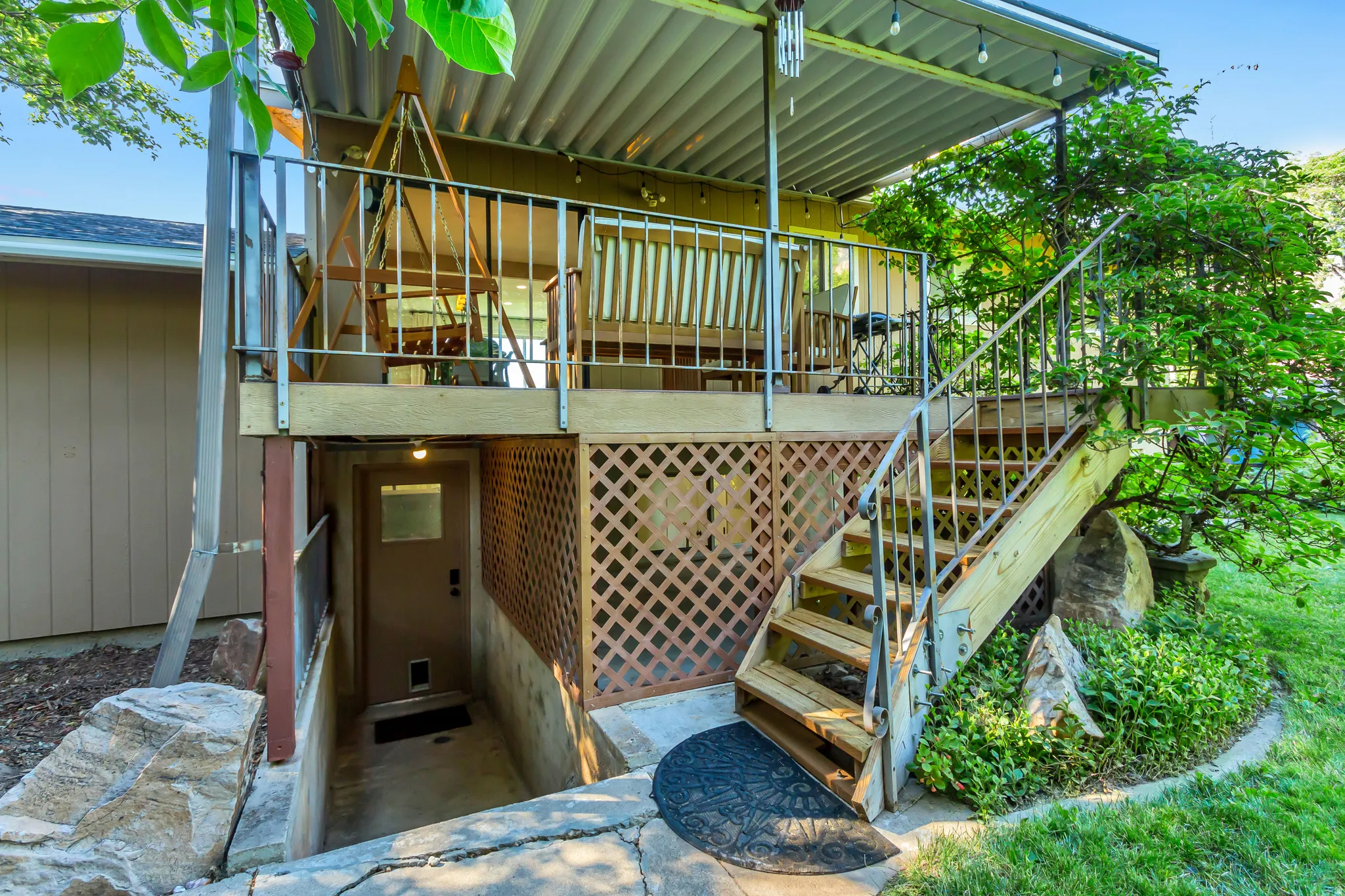 Elevated wooden deck featuring metal railings and a corrugated metal awning