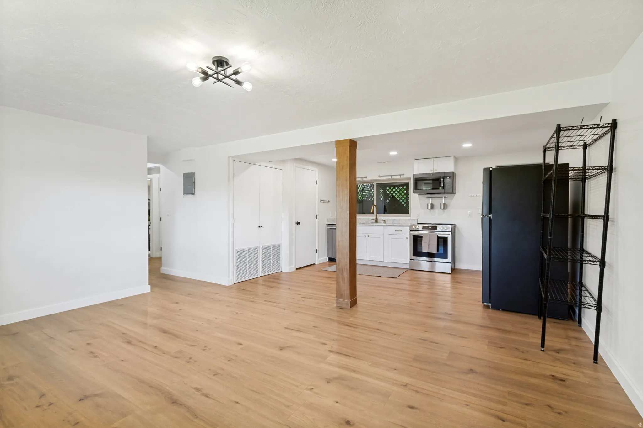 Open-concept living space featuring wood-finish flooring and a contemporary light fixture