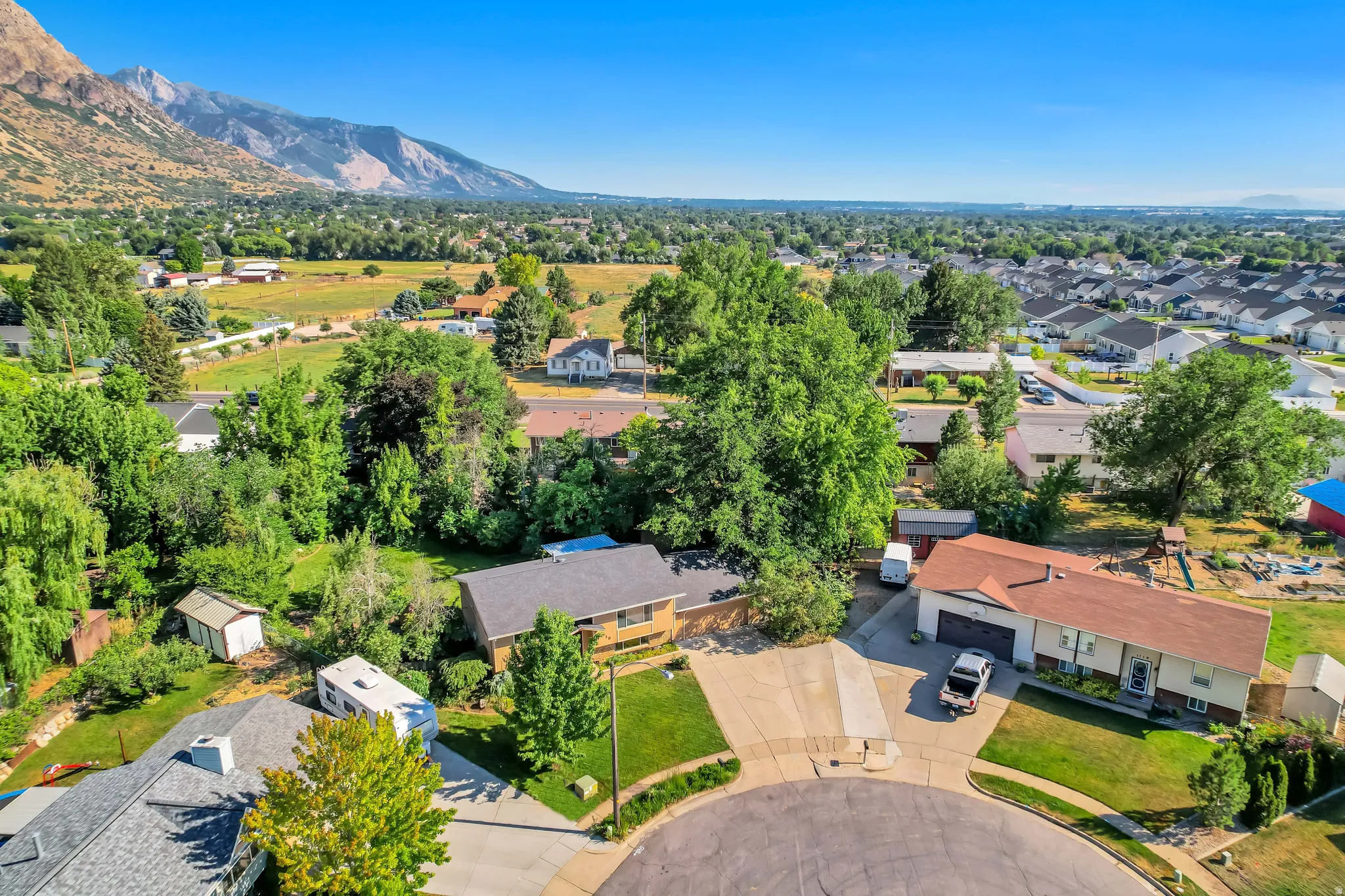 Elevated aerial perspective showcasing a cul-de-sac property with a brown-shingled roof and an attached two-car garage