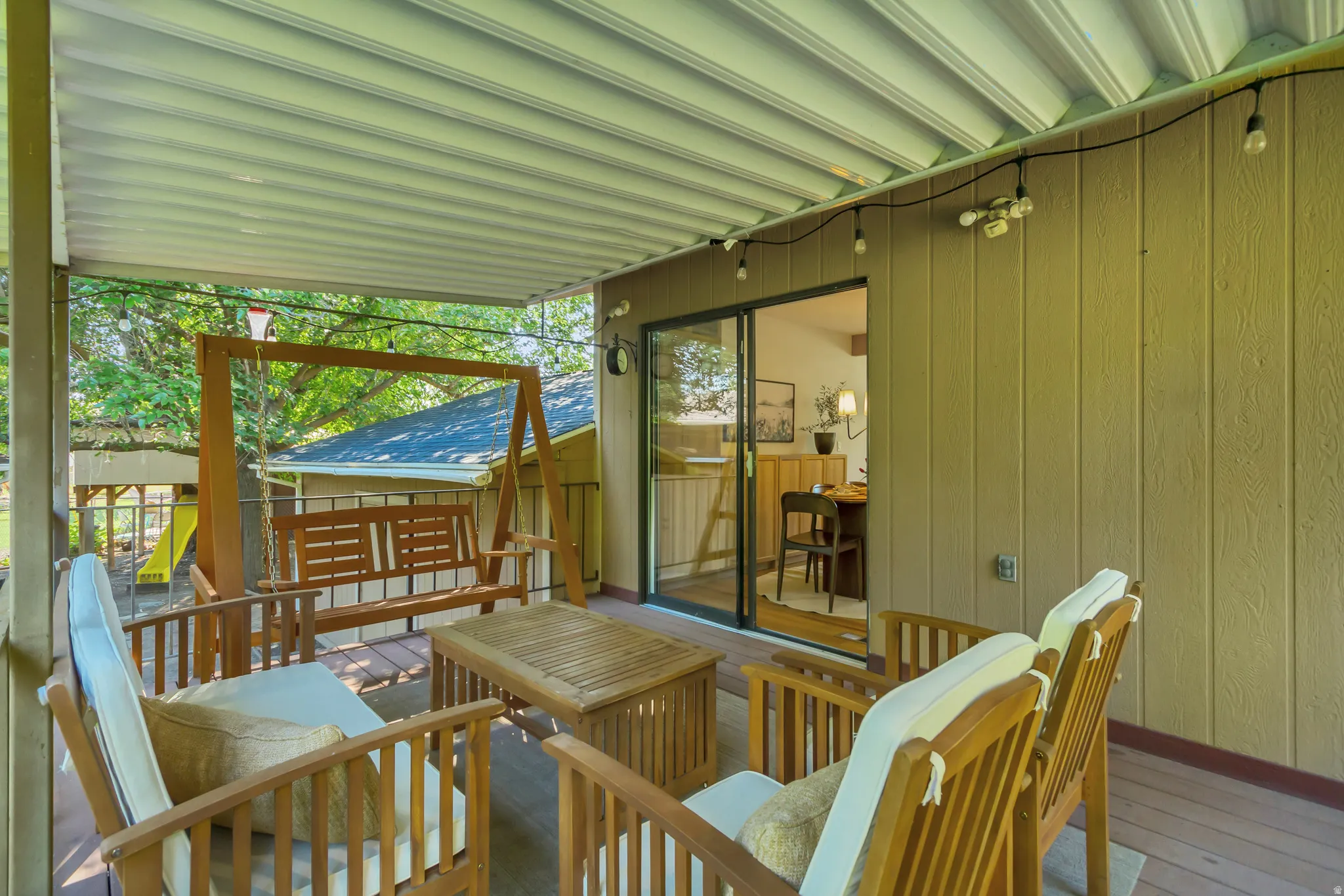 Covered outdoor deck featuring a wooden swing, recessed lighting, string lighting, and direct access to the interior via a sliding glass door