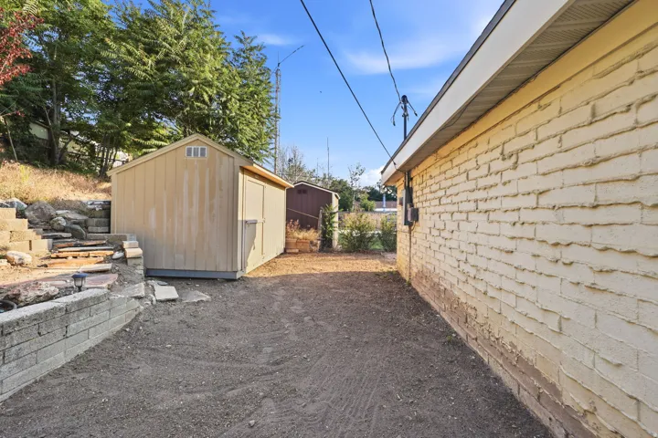 Brick exterior with a detached shed and a retaining wall